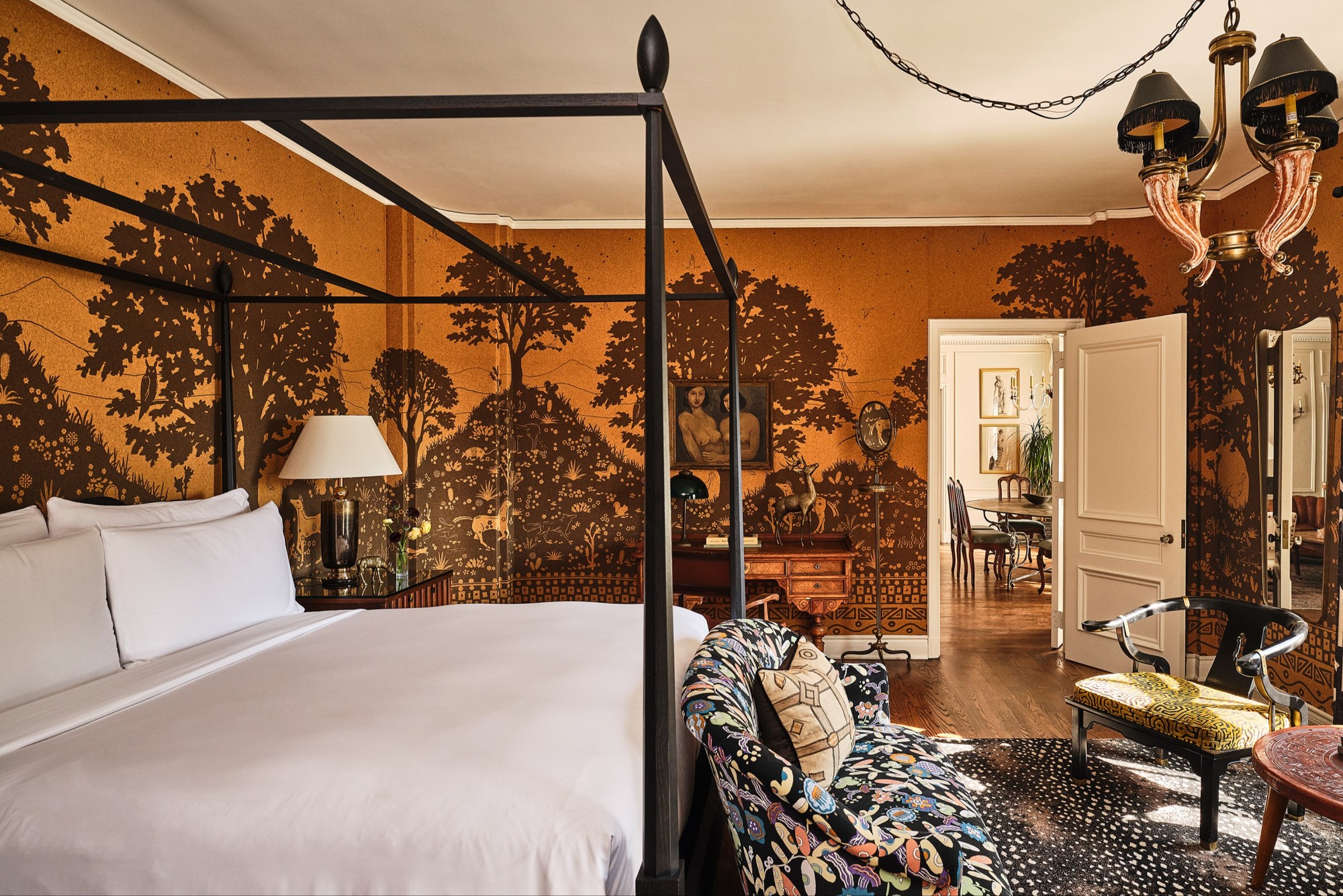 a beautiful bedroom with a four-post bed and orange wallpaper depicting trees