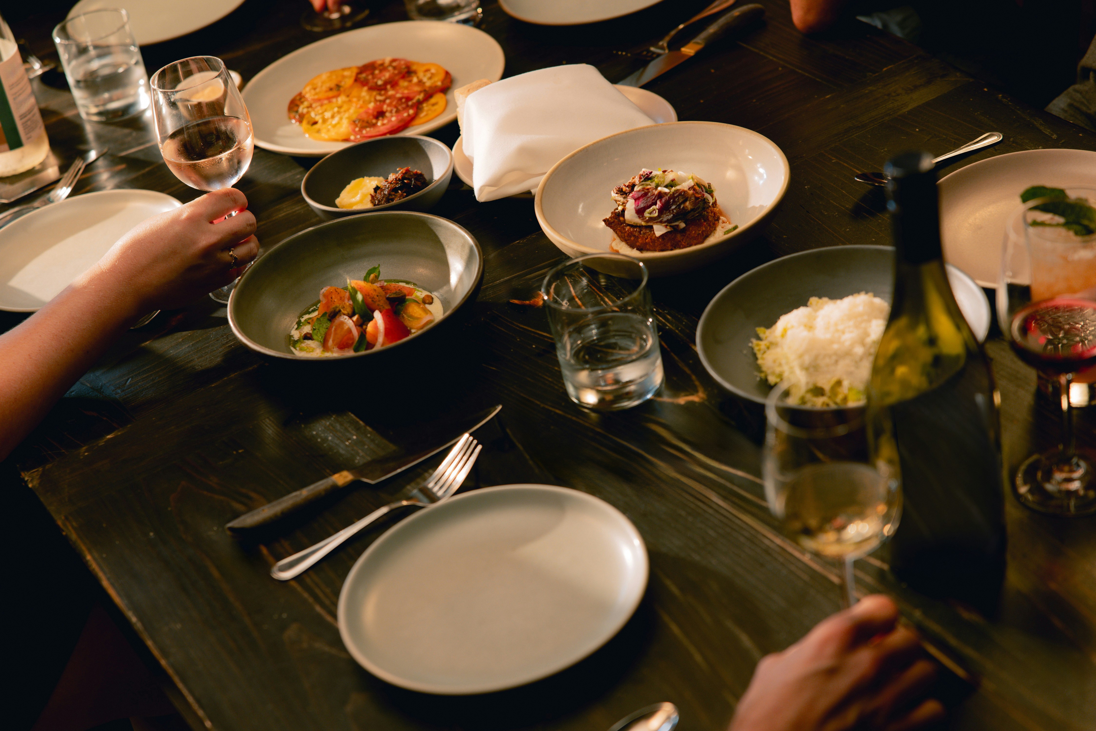 A dining table covered with food on dark plates and bowls