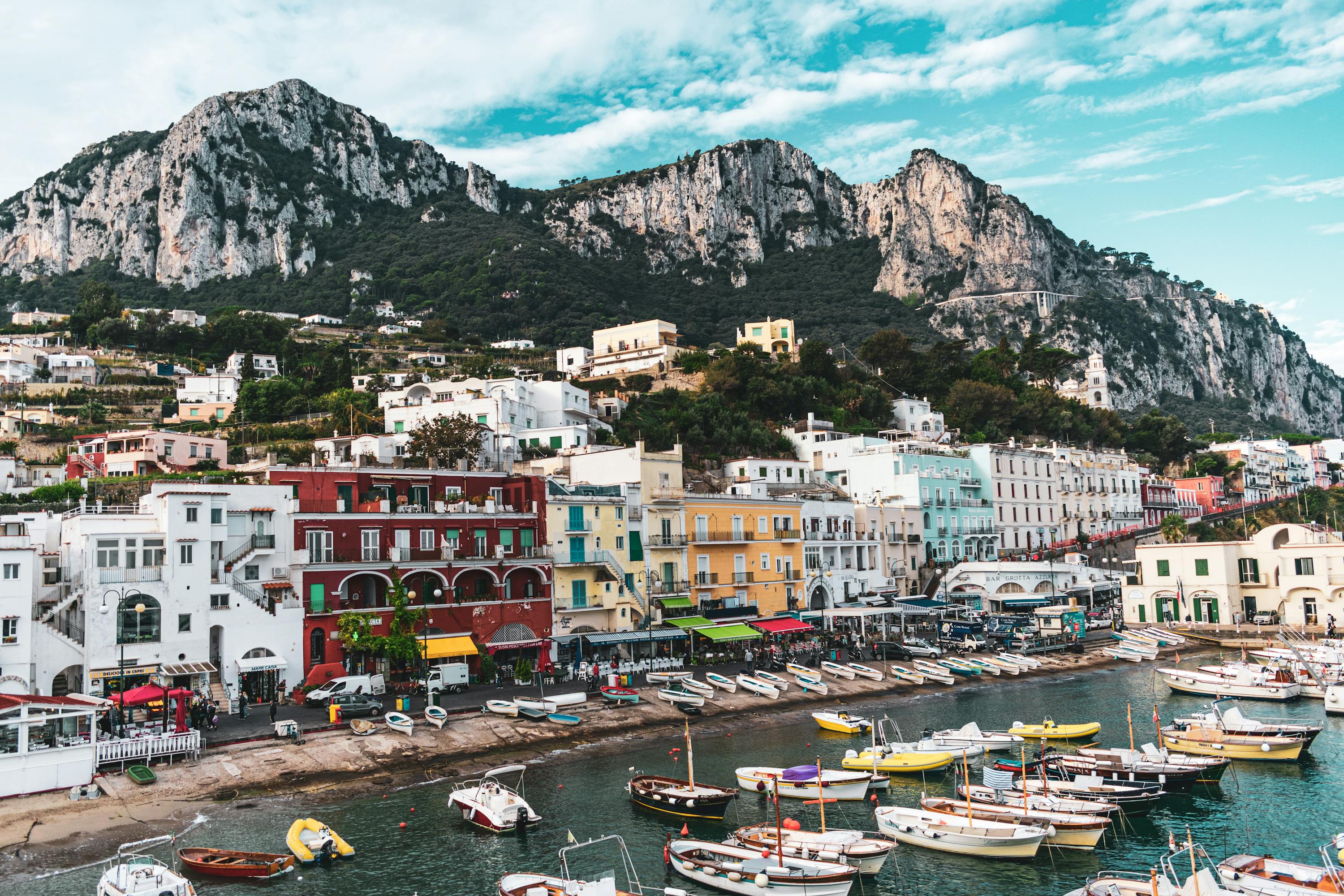 A seaside village with a mountains range in the background during the daytime