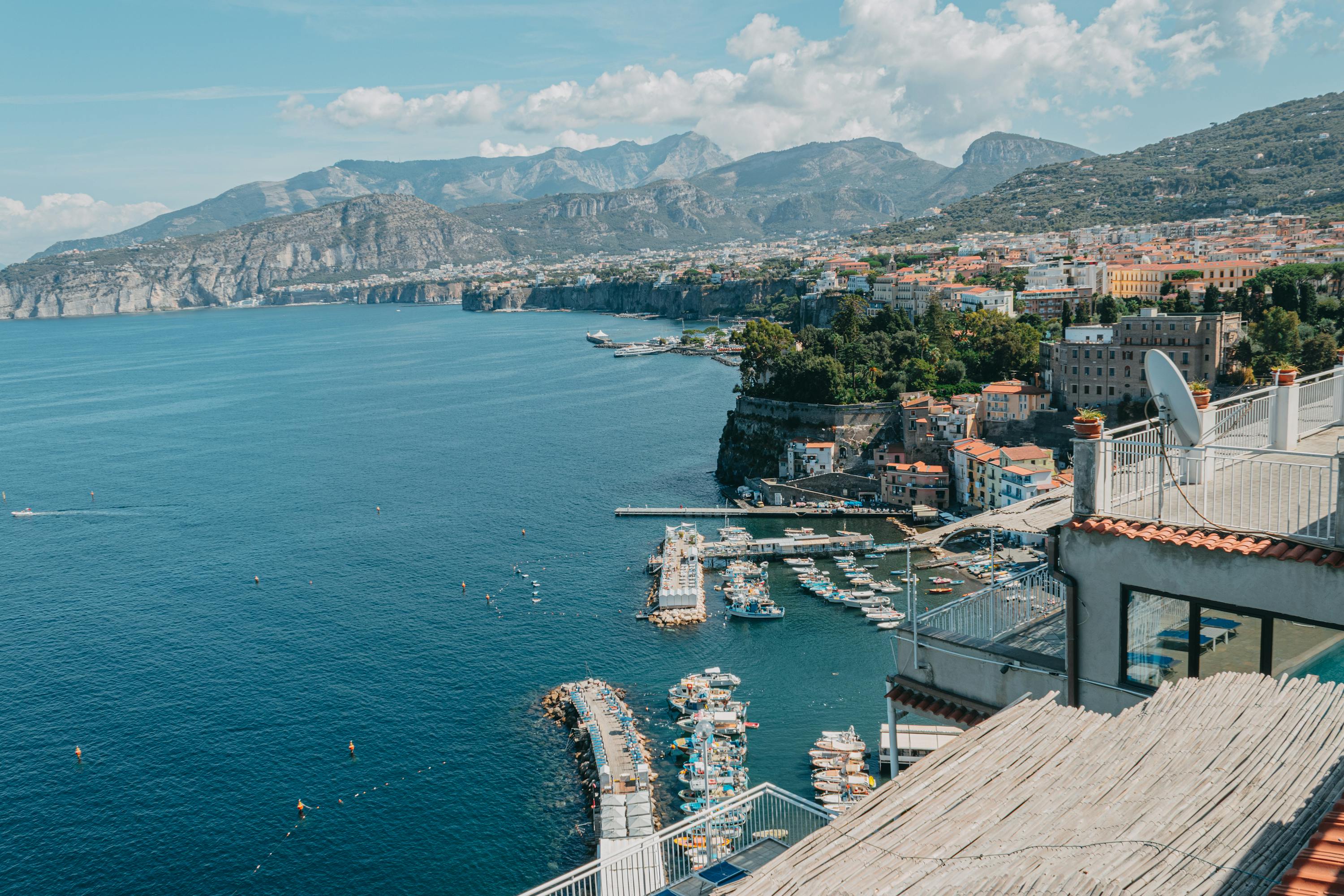 A view of a pier in the sea with mountains in the distance