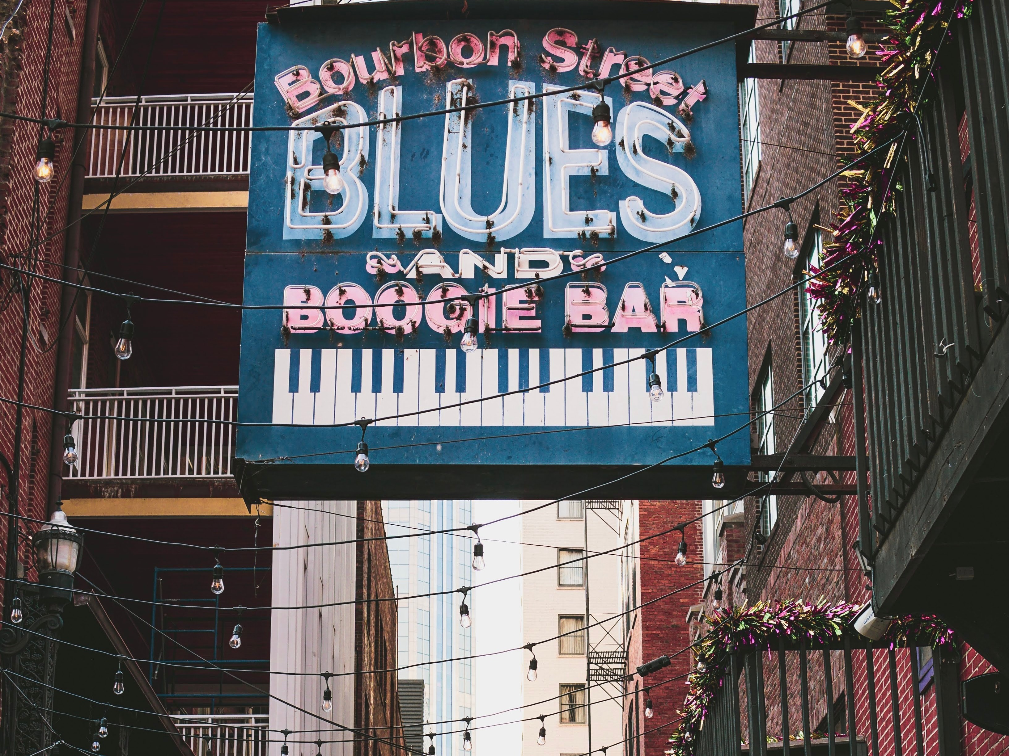 A blue sign above and alleyway reading "Bourbon Street Blues and Boogie Bar"