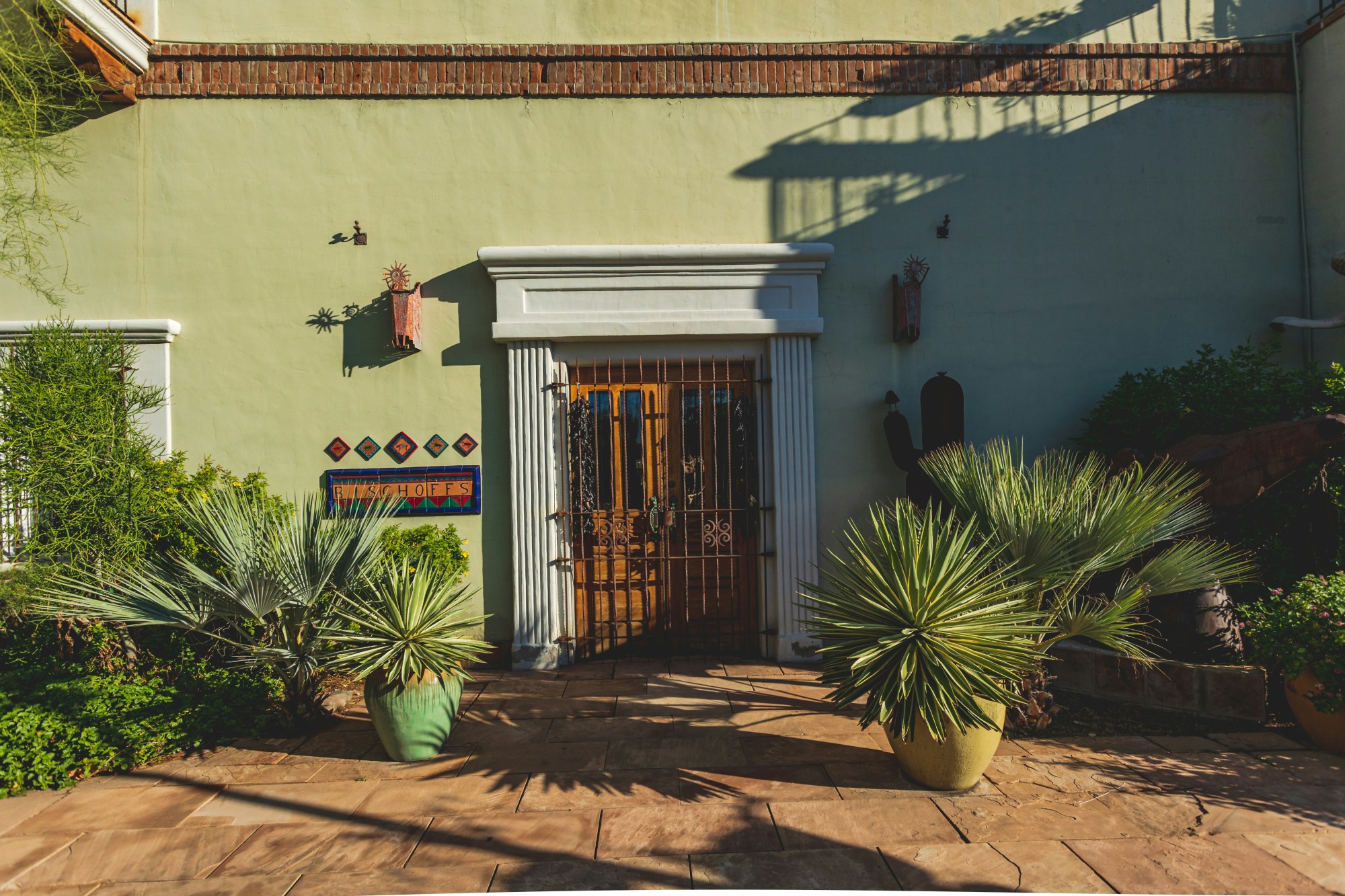 A green painted building with a wooden door and black gate over it