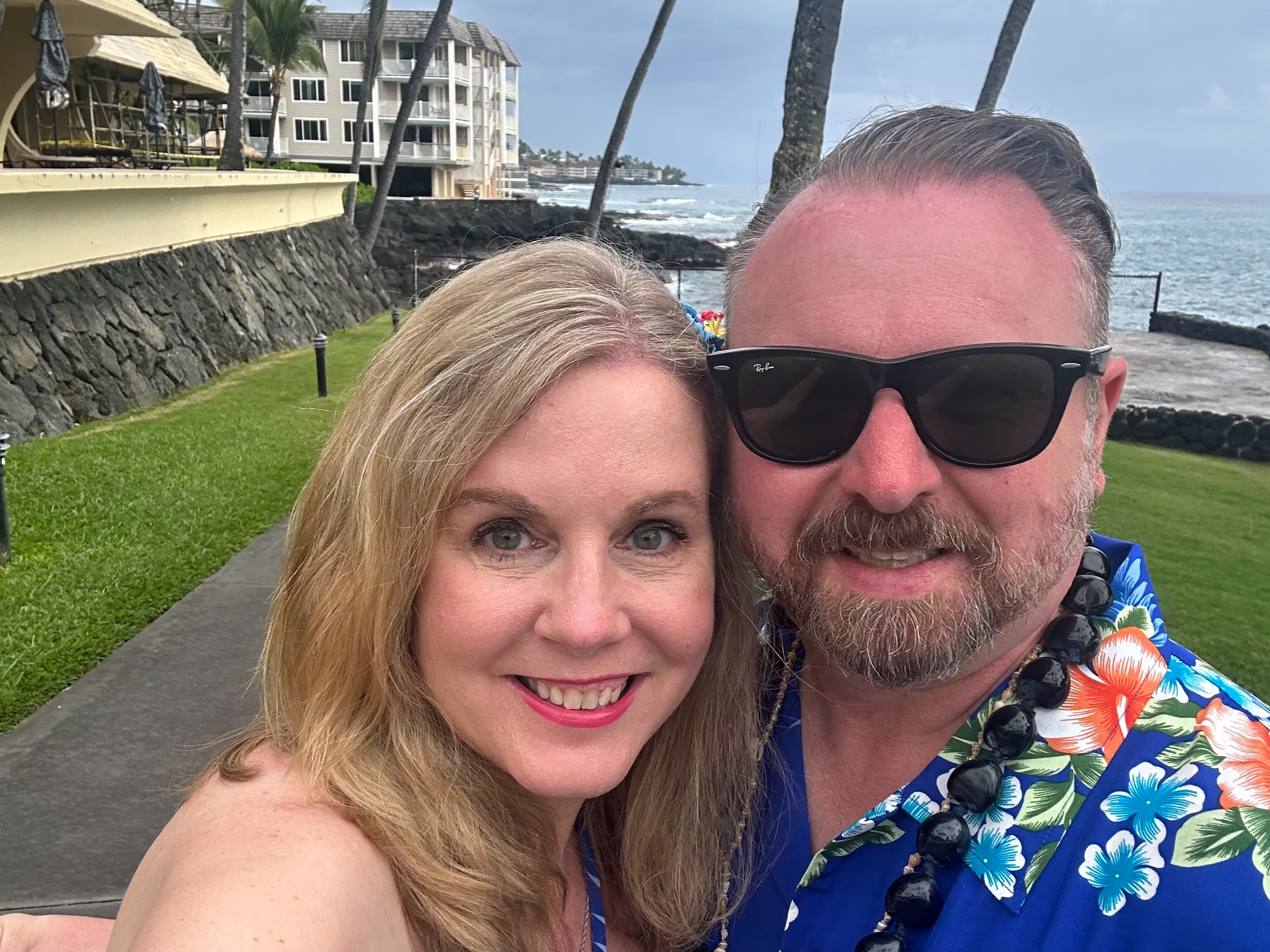 A couple is posing in front of the sea during the daytime.