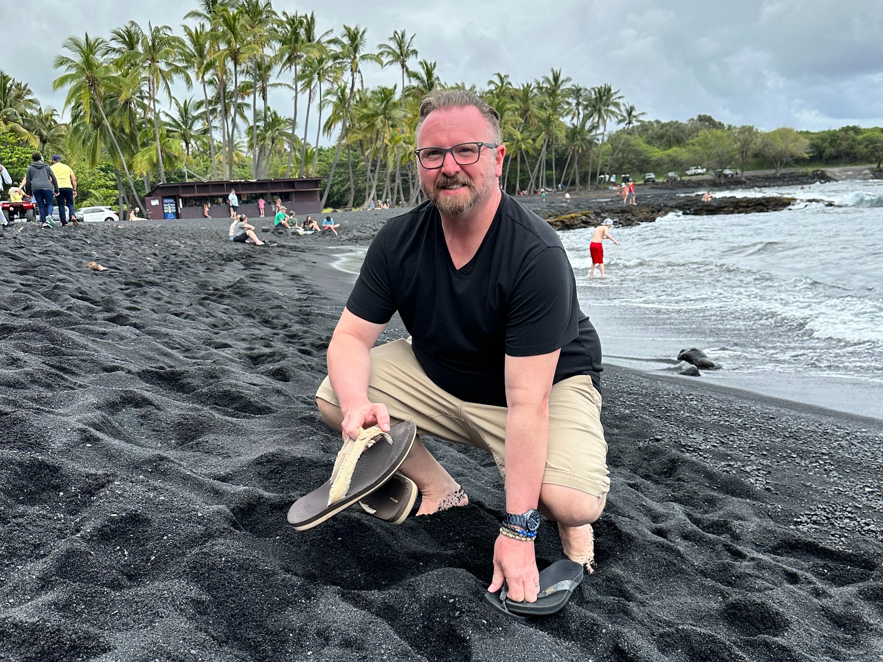 A person sitting on a black sand beach.