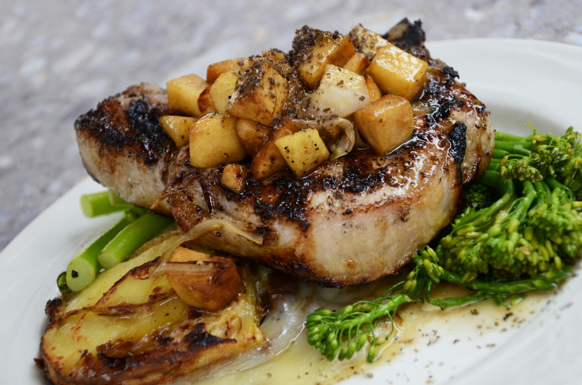 Grilled meat on a plate, topped with marinated vegetables