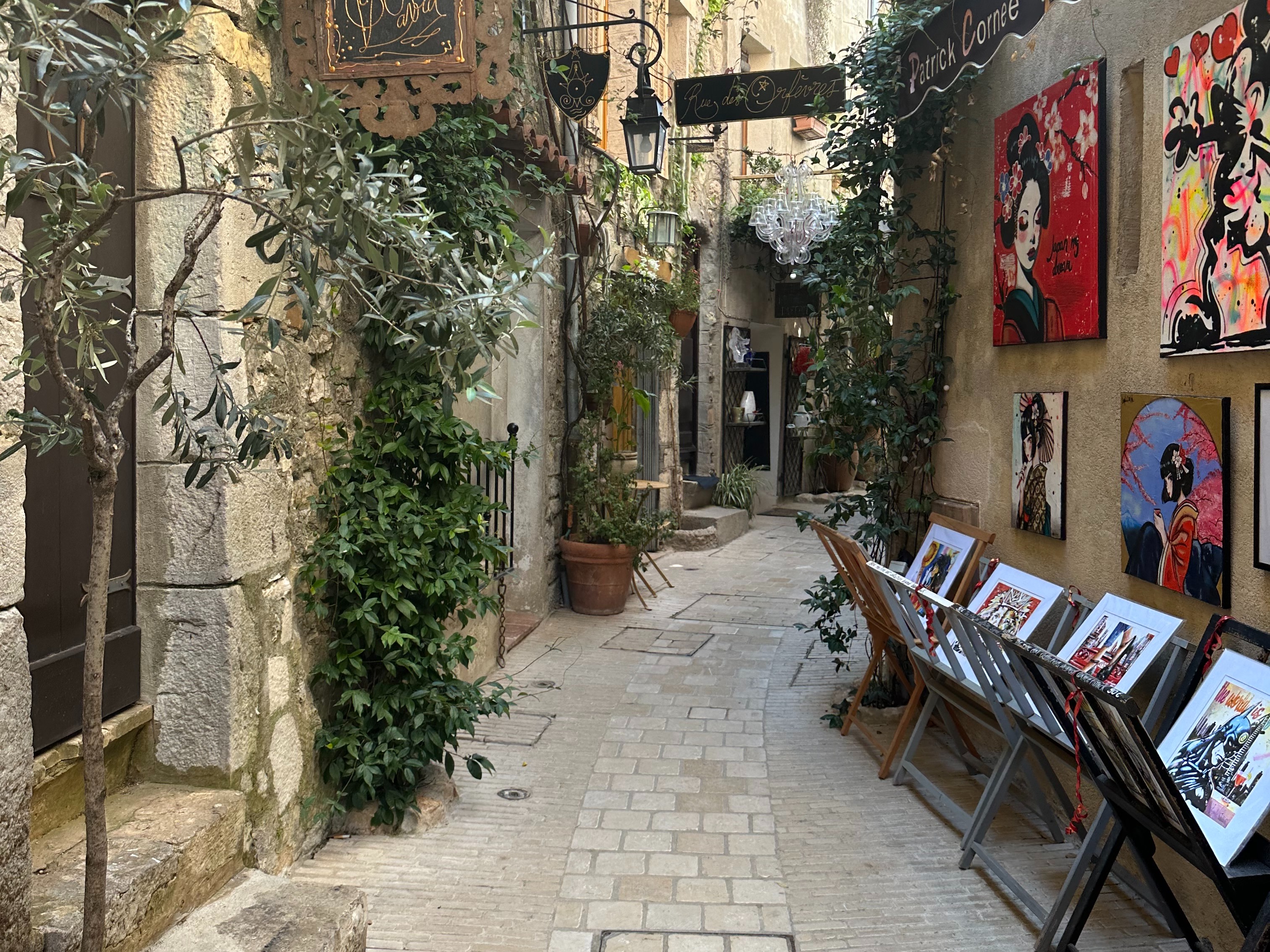 A charming alleyway adorned with artwork and a quaint signboard, evoking European culture.