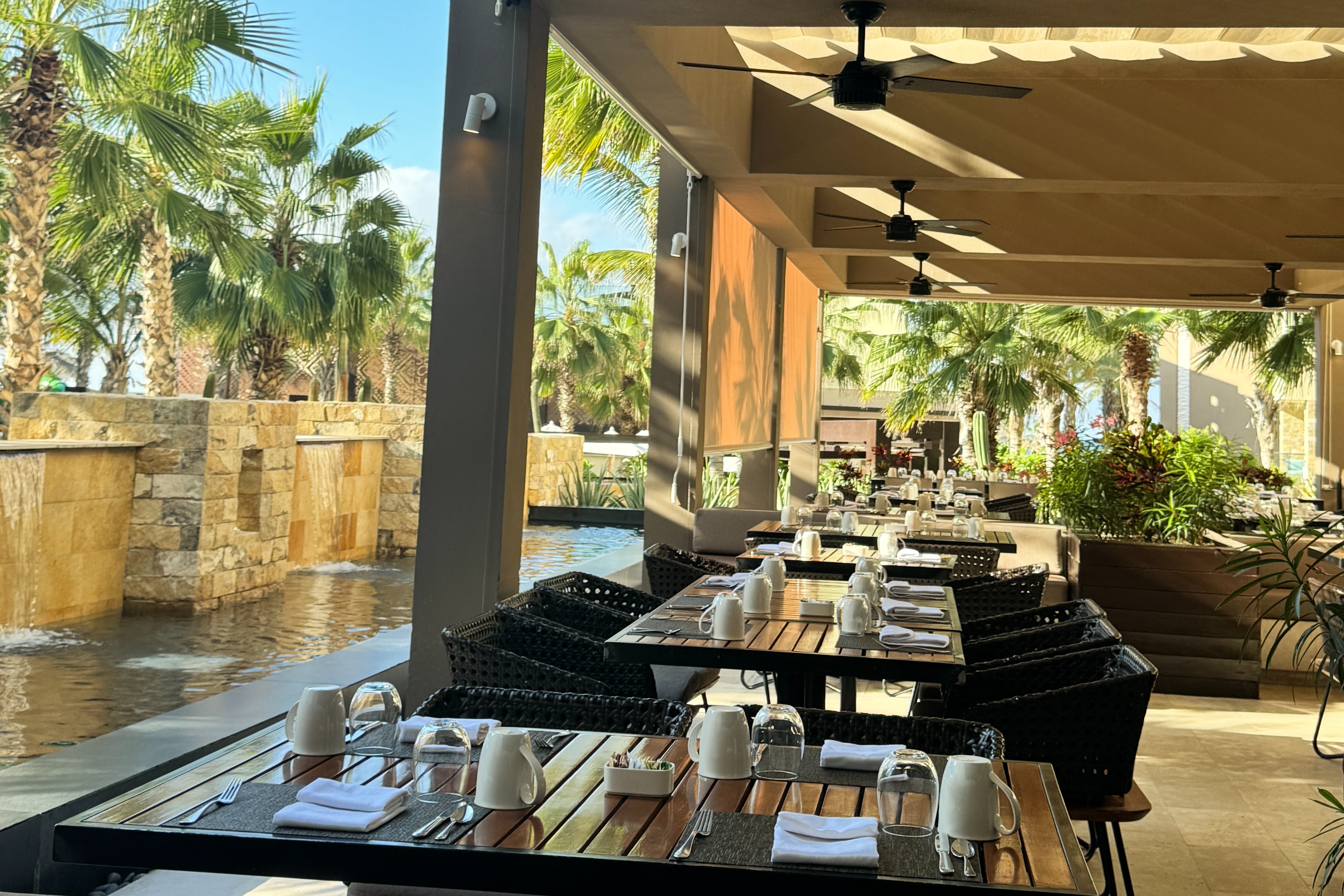 Poolside dining at Hard Rock Los Cabos under a covered patio on a sunny day.