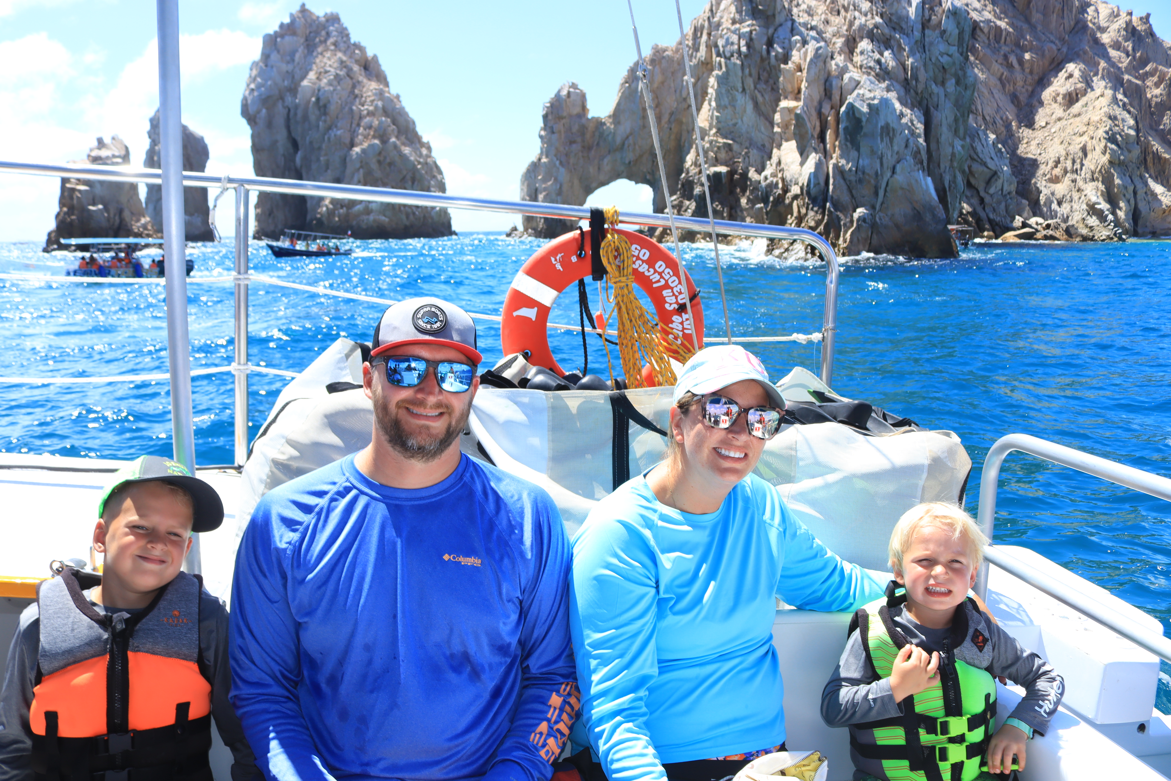 A family on a boat exploring El Arco on a sunny day.