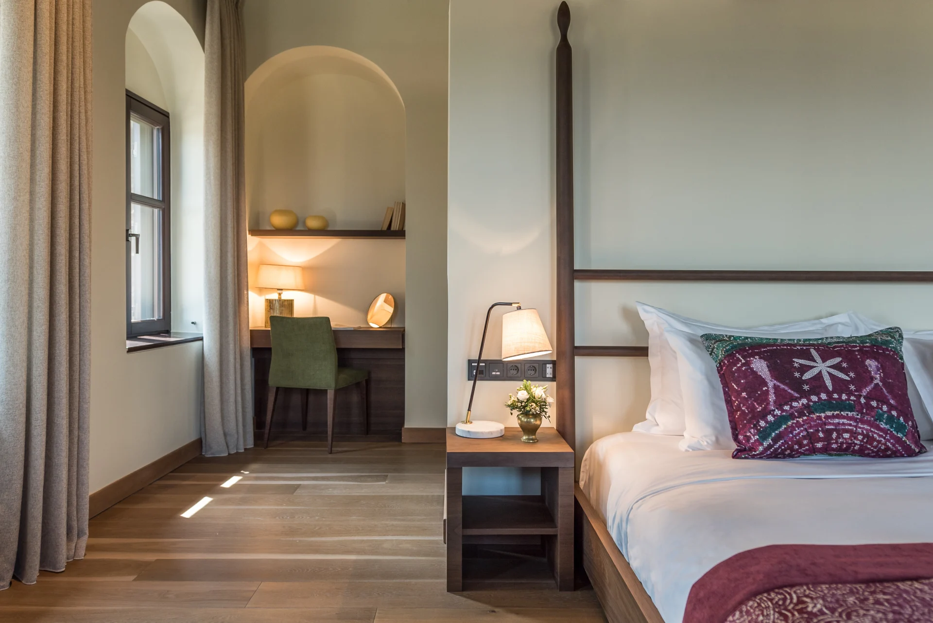 a zen hotel room with wooden floors and a bed decorated with patterned fabrics
