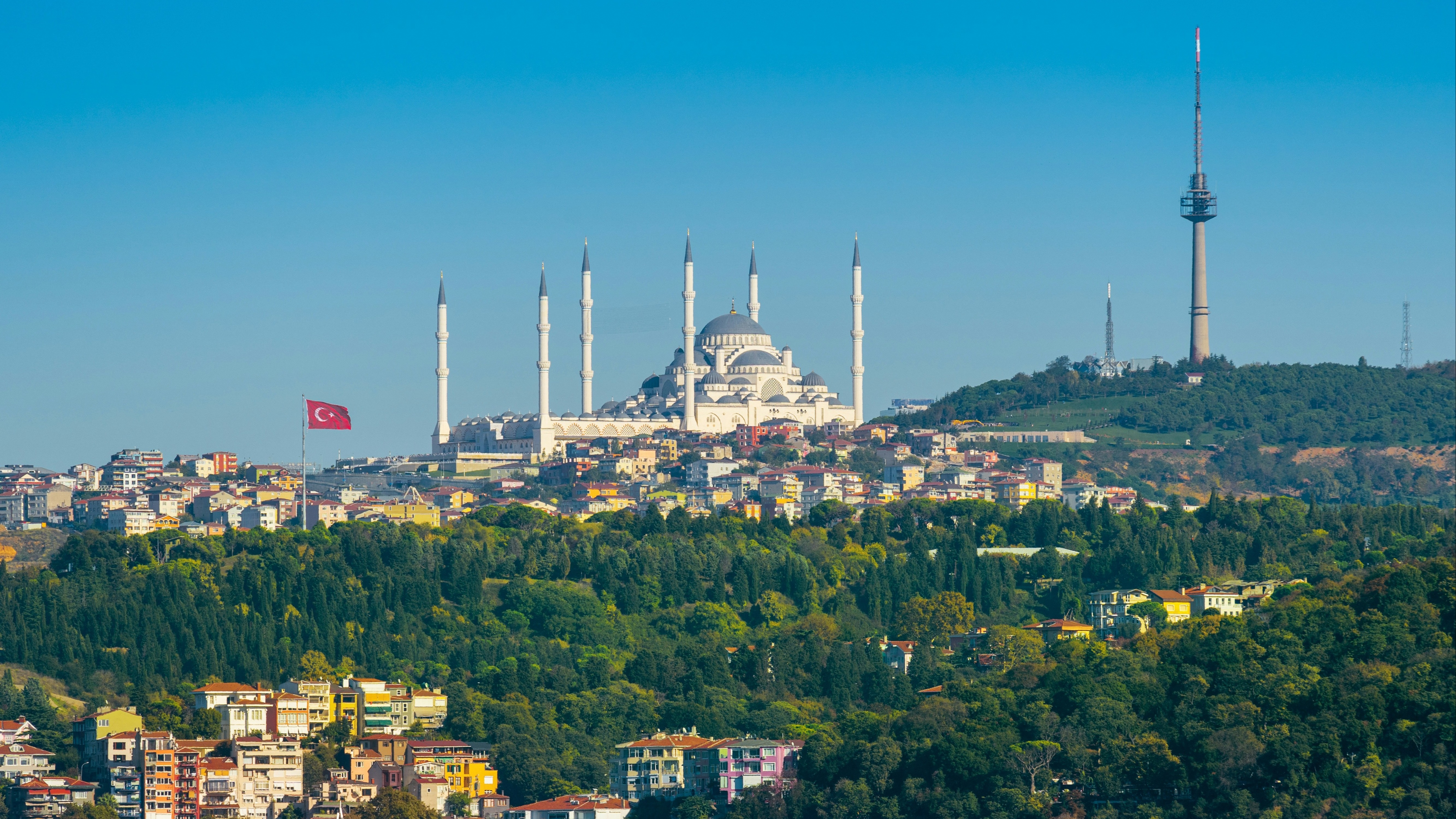 The image shows a panoramic view of Istanbul, highlighting the Camlica Mosque with its six minarets and the surrounding urban landscape.