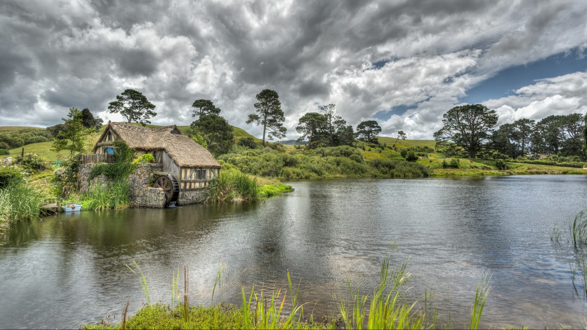 The Hobbiton set from The Lord of Rings films featuring small houses tucked into grassy hills along a river.