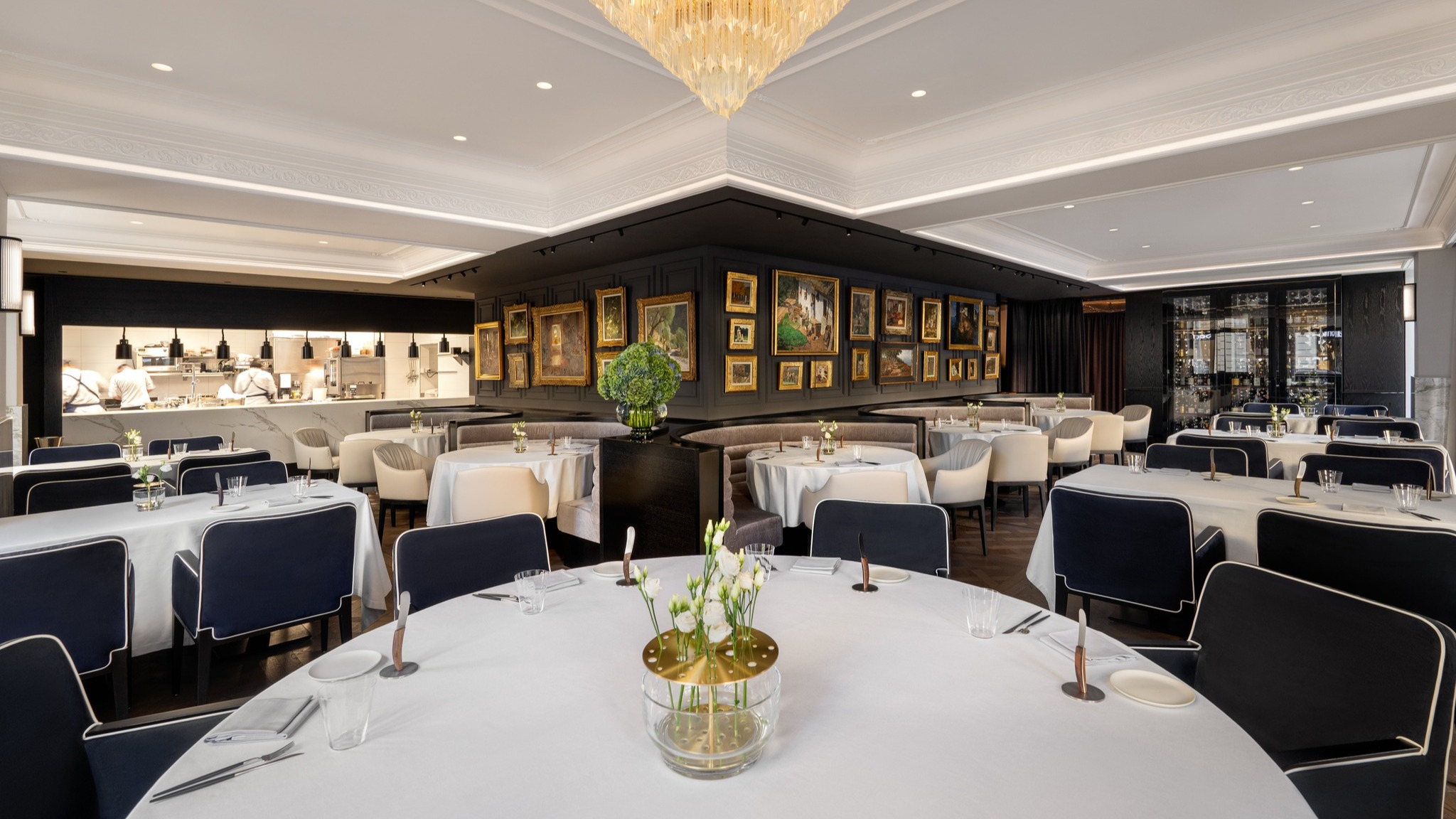 An empty restaurant with tables covered in white table clothes.