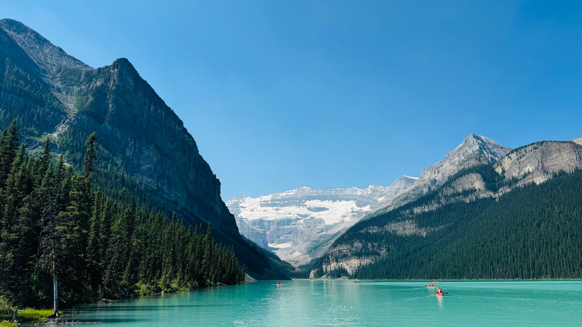 A bright blue lake between snow-capped mountains.