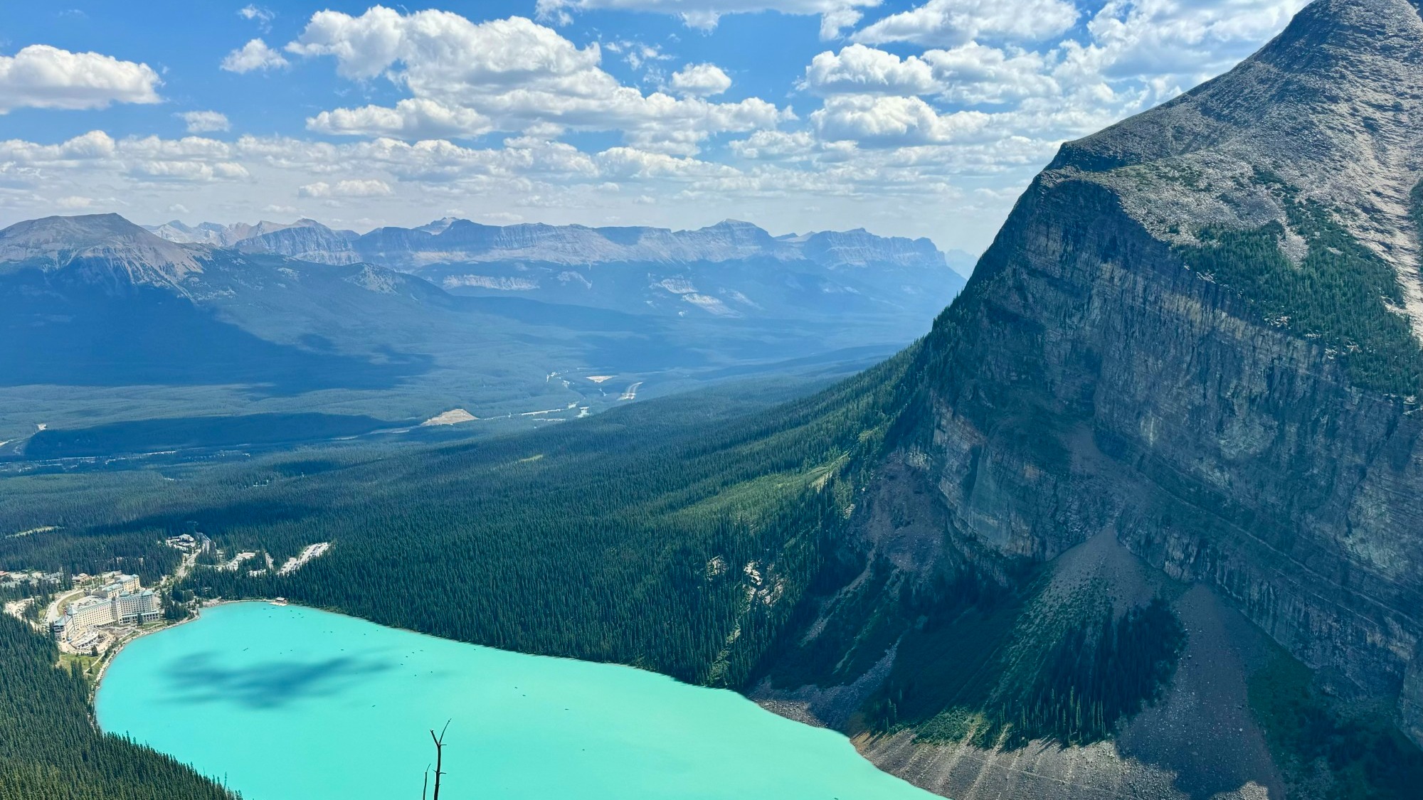 An aerial view of a bright blue lake and glacial mountains.