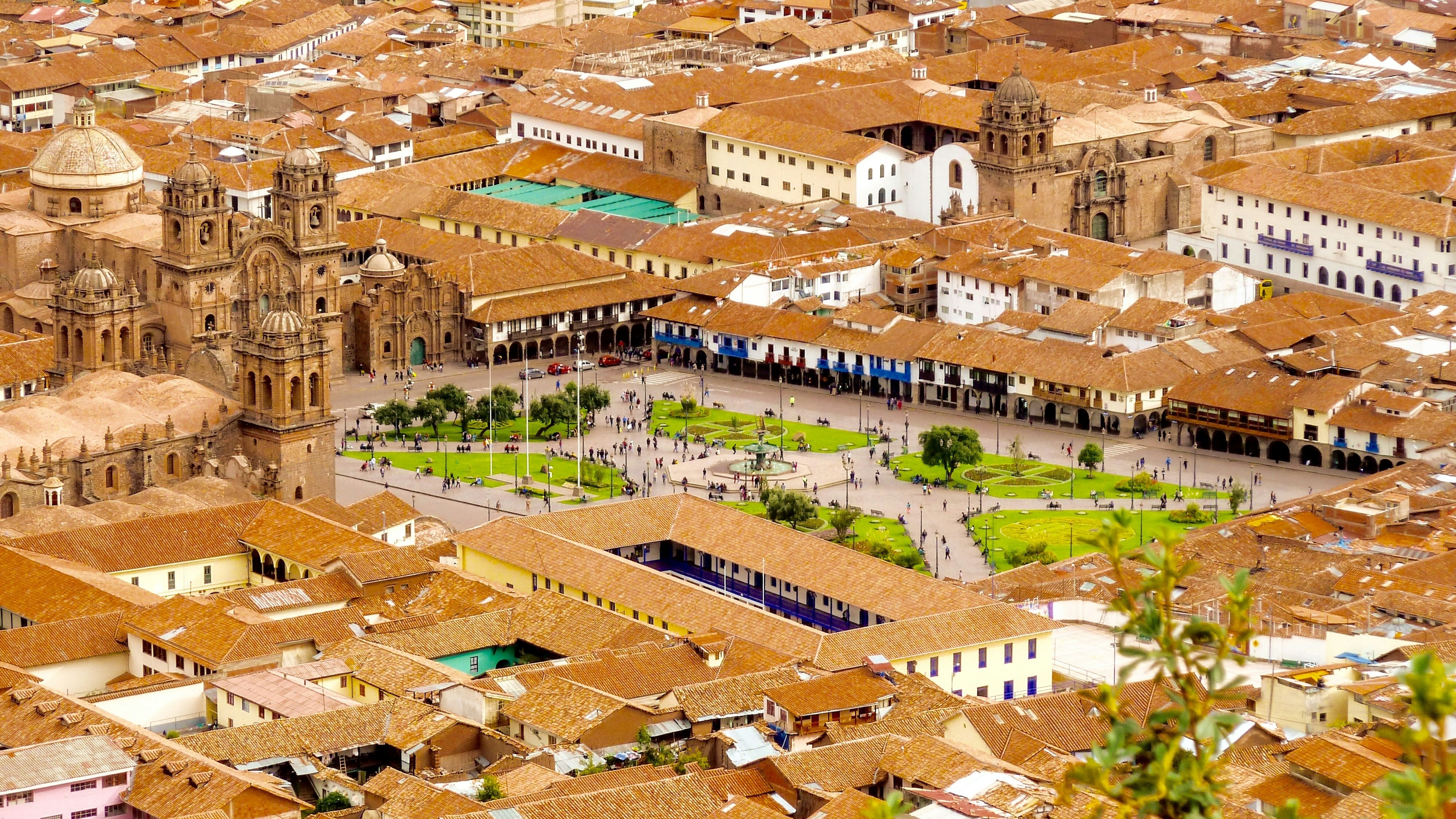 An aerial view of a densely packed urban area with numerous buildings and a prominent central square with a large church.