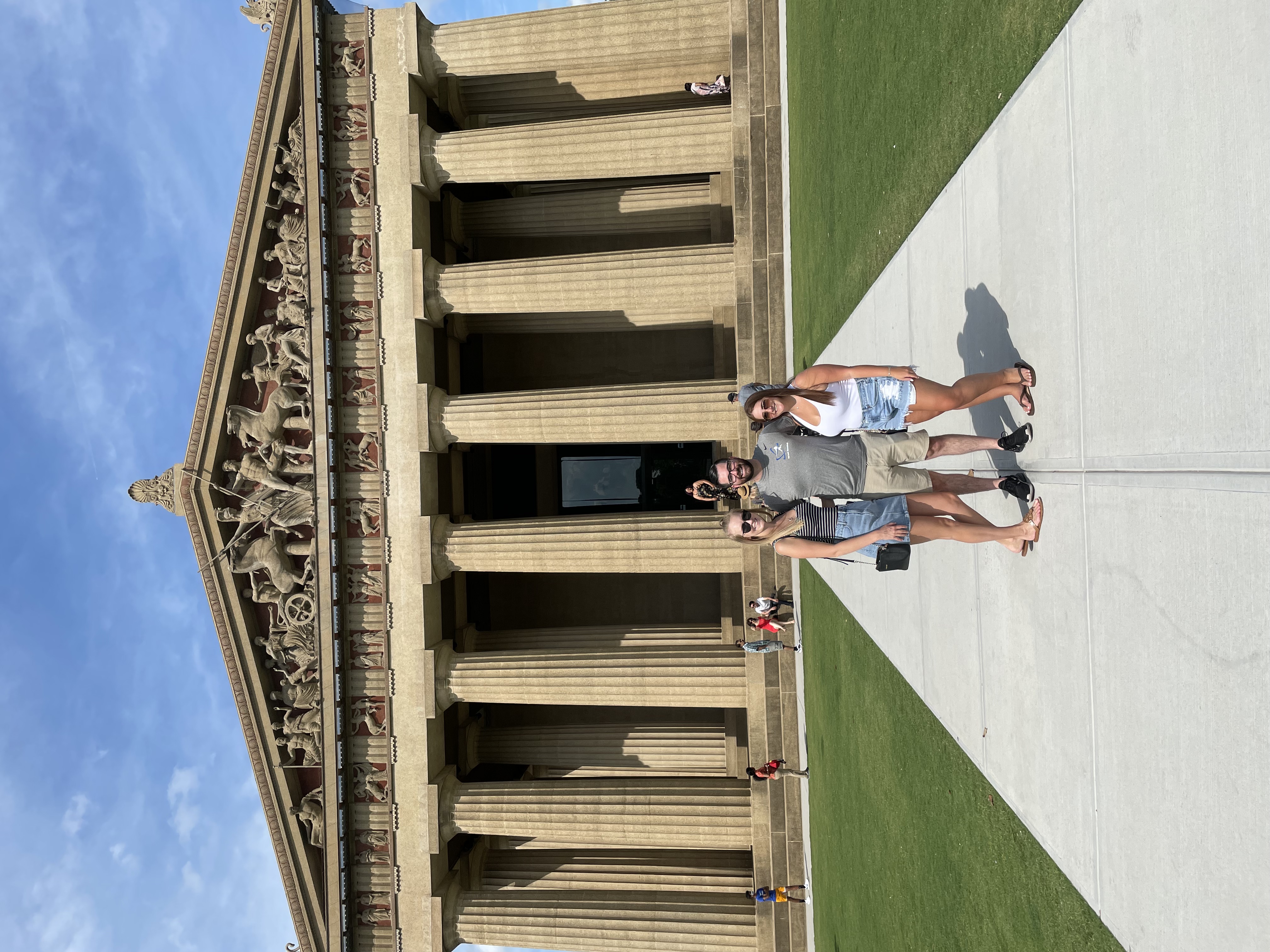 A group of people in front of an ancient-looking building in a park during the daytime