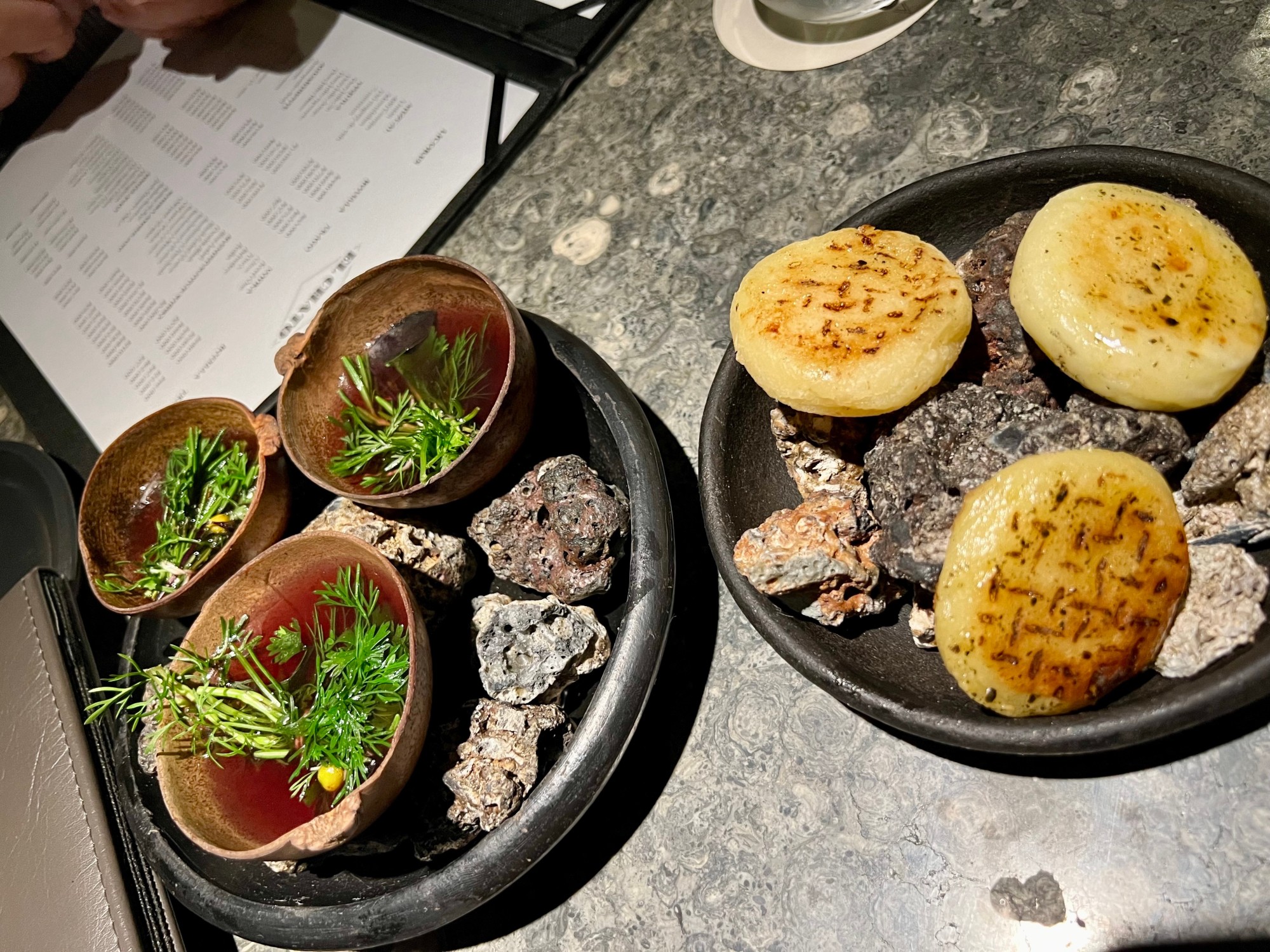 Food in black bowls on a marble table top