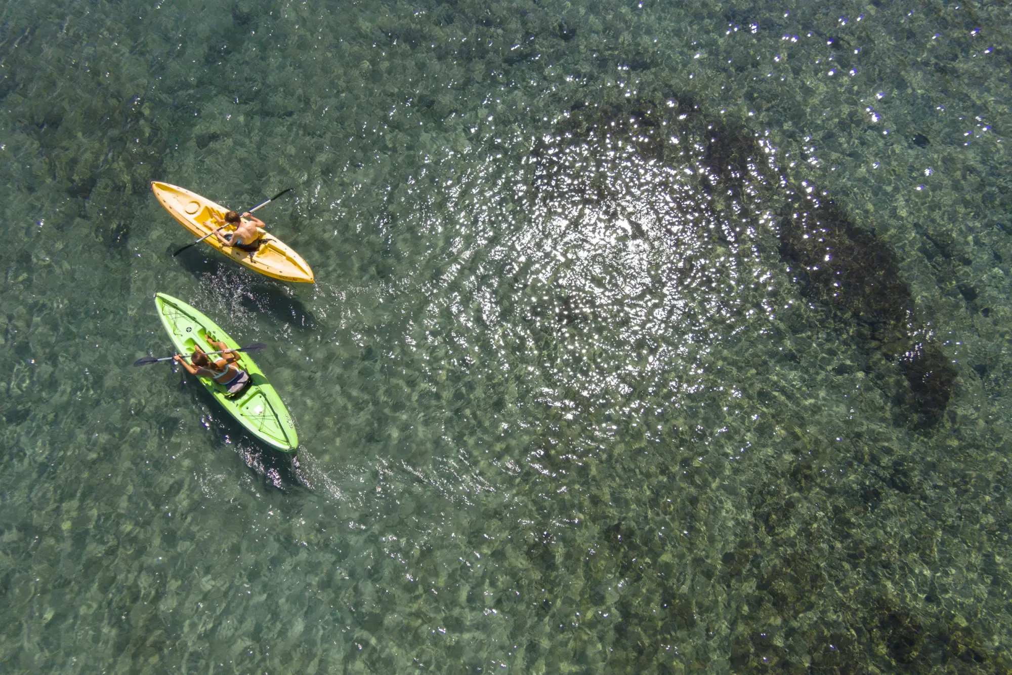 Aerial view: Two kayakers paddle along just off shore (unseen) somewhere in Costa Rica
