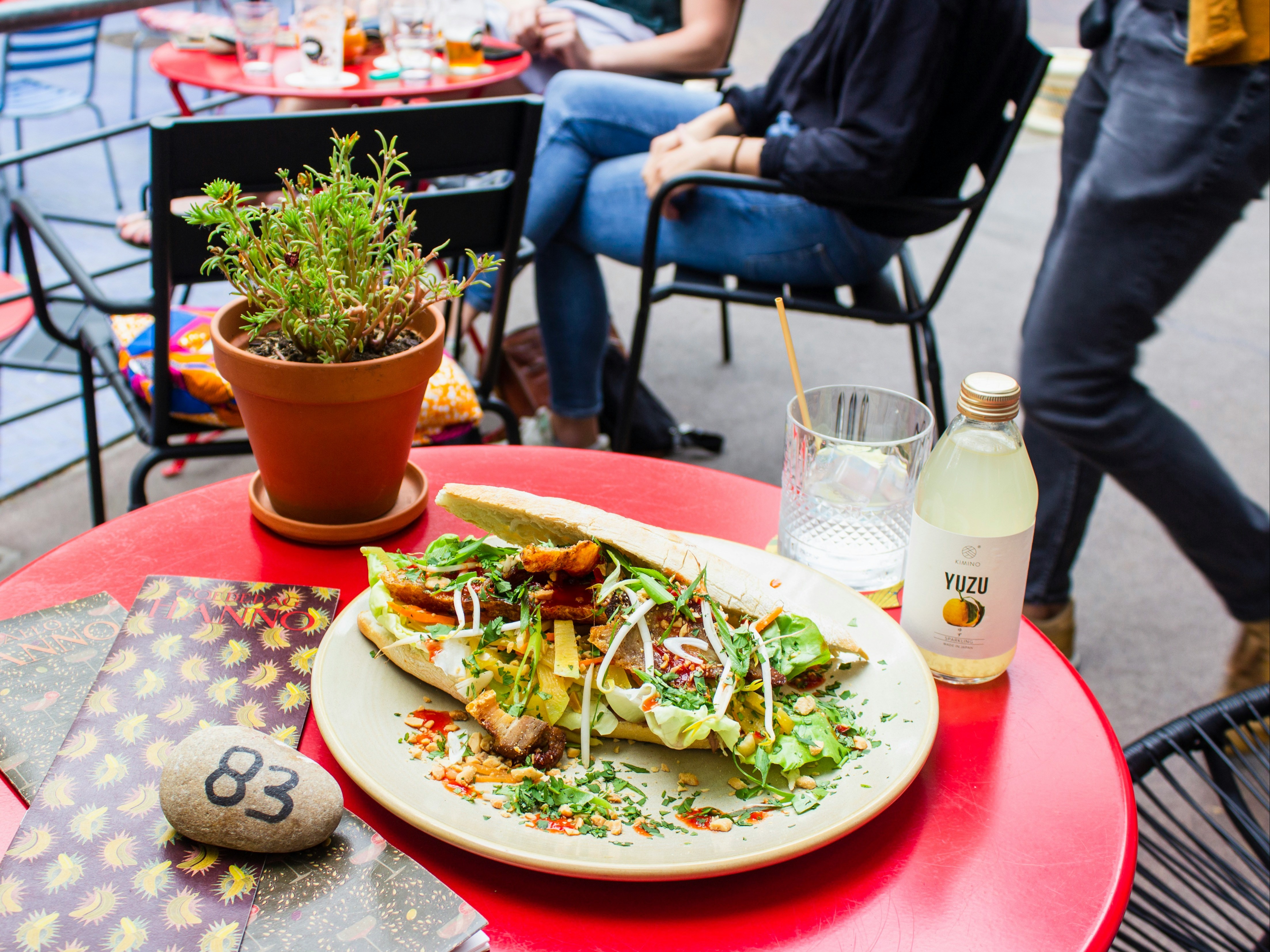 A plate of healthy sandwiches on a red table with drinks and other diners in the background.