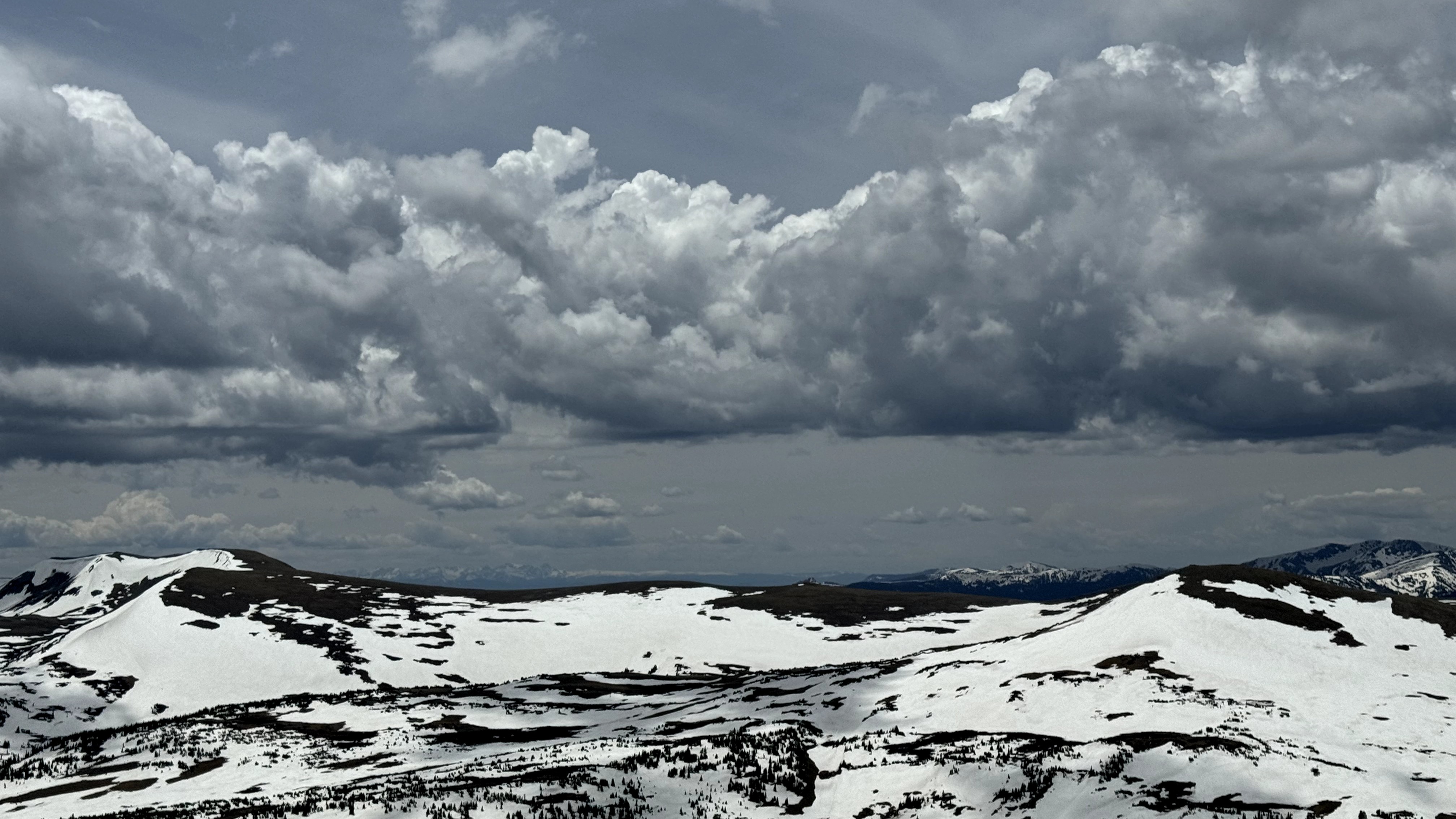 A snowy mountainous landscape under a dramatic cloudy sky.