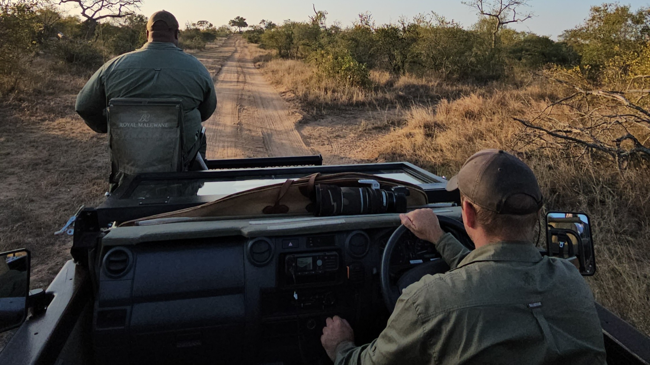 Two men driving through on the veldt in a jeep.