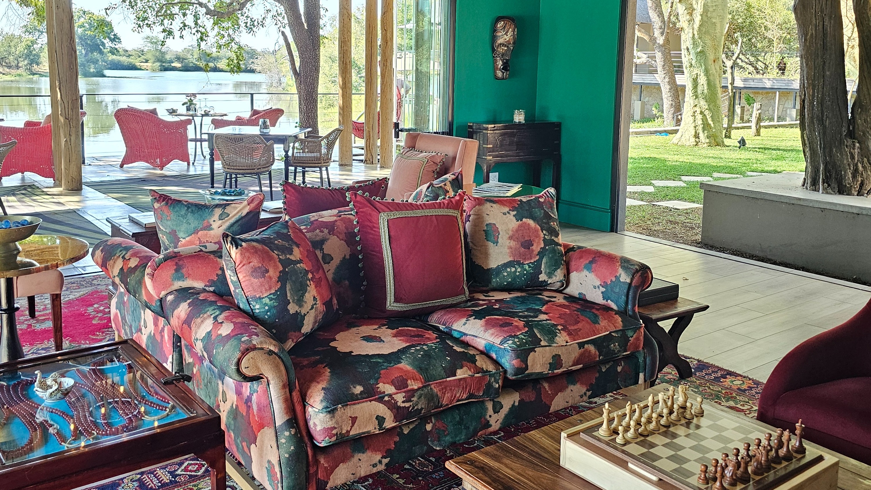 A colorful loveseat in a seated area with floor-to-ceiling windows behind.