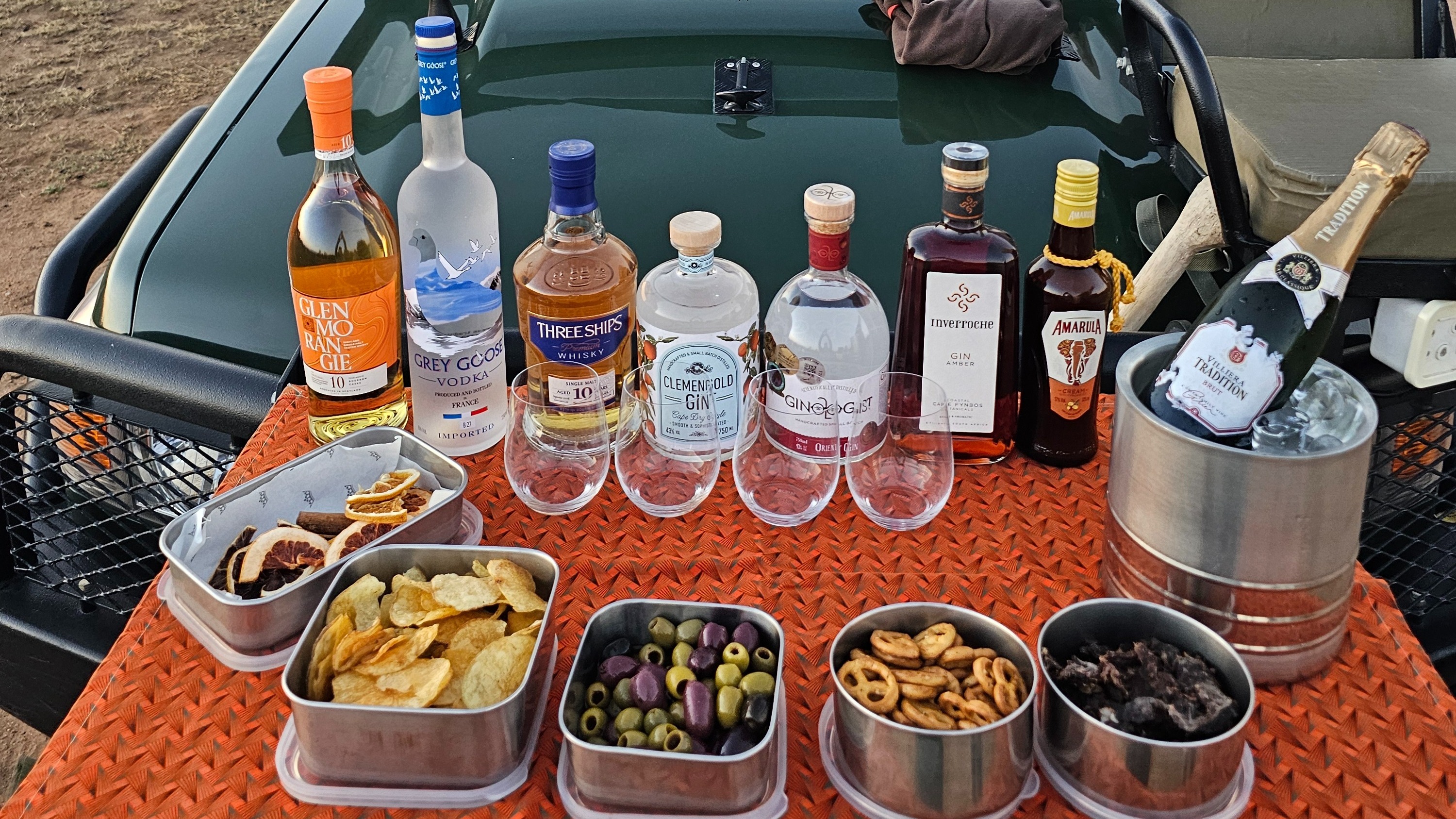 A table set up with tins of food and various bottles of alcohol.