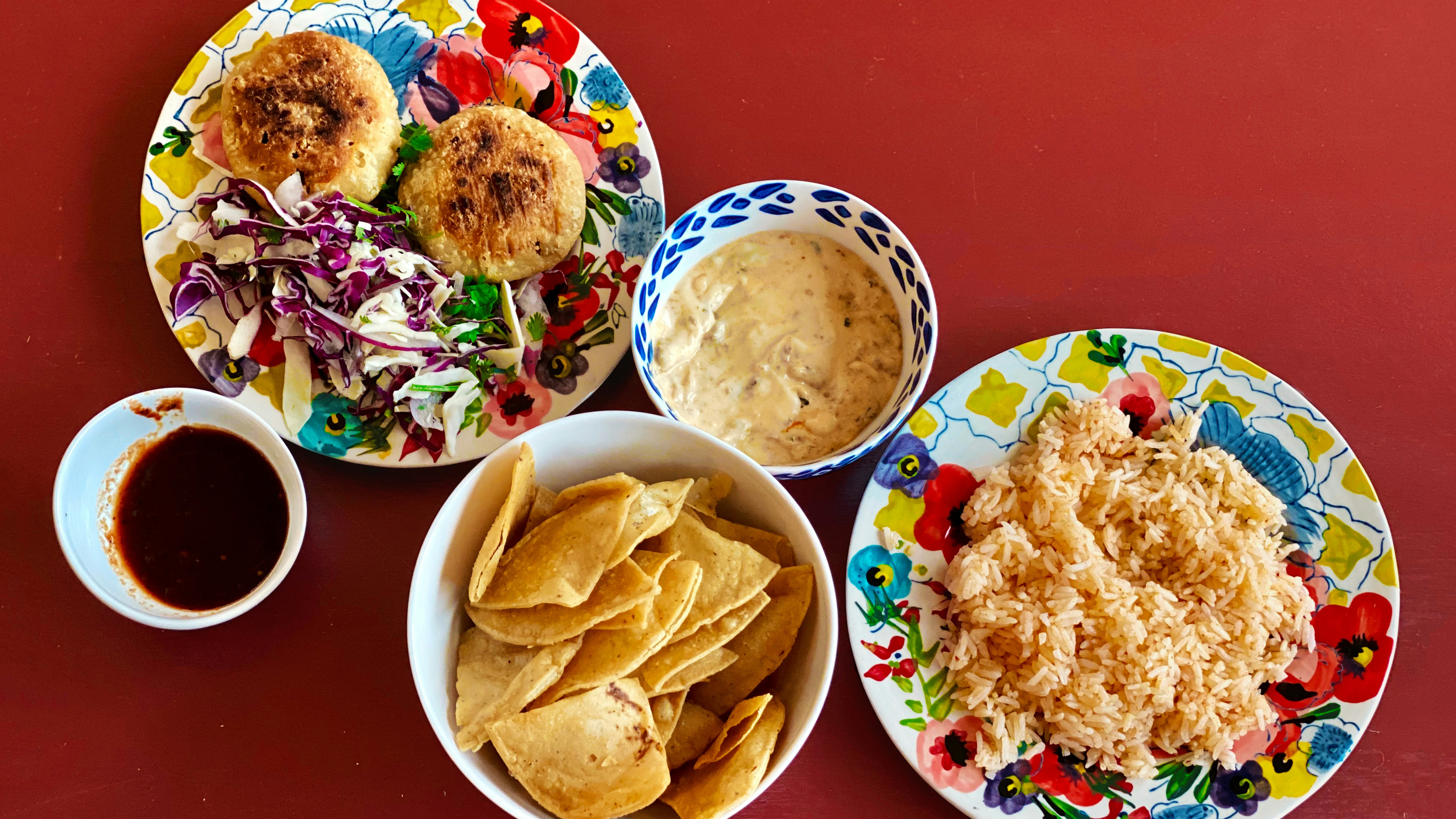 Plates of Mexican food arranged on a red table top.