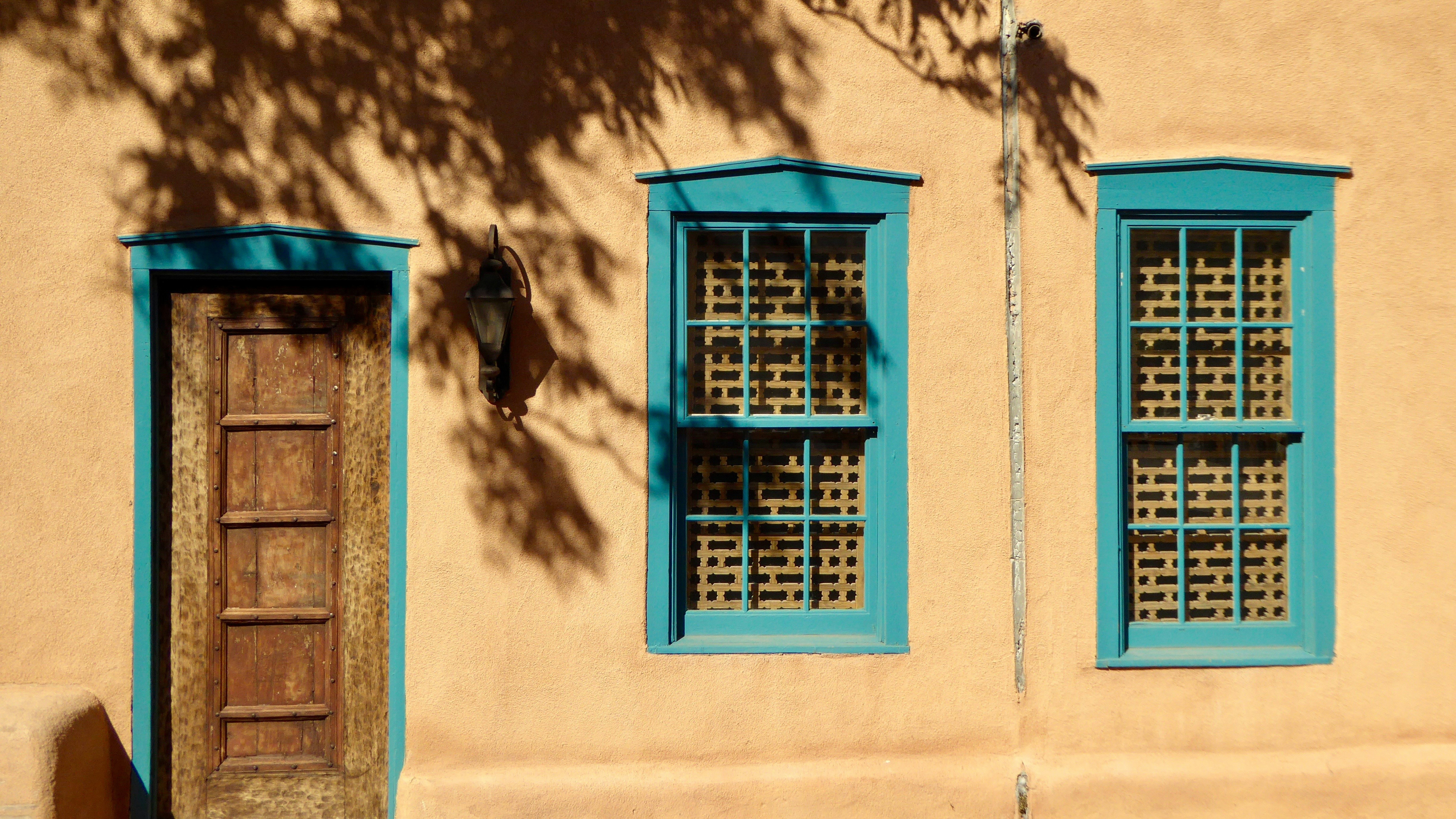 Two blue windows in an adobe building.