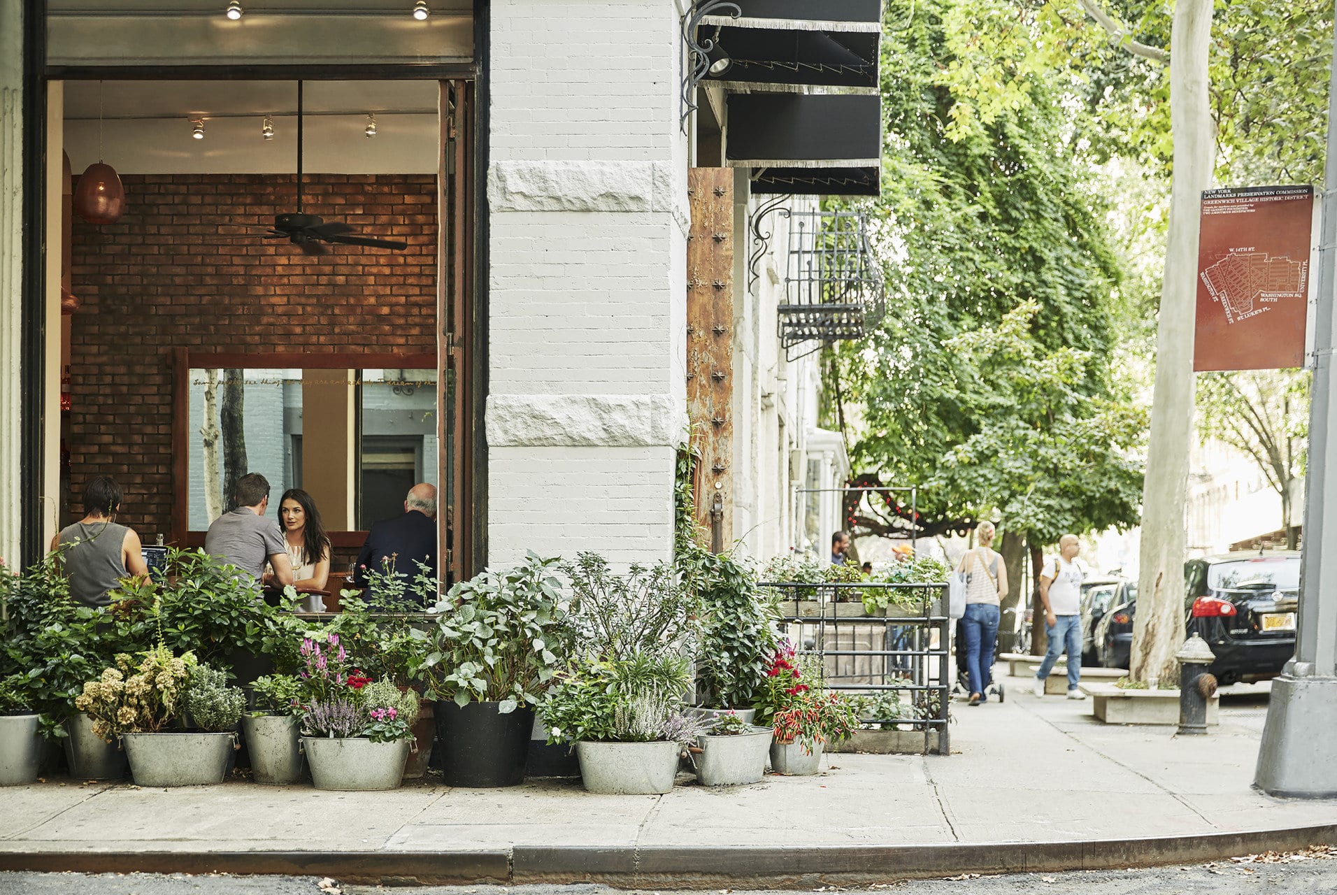 A relatively quiet corner of Greenwich Village in NYC, with dozens of potted plants outside a cafe