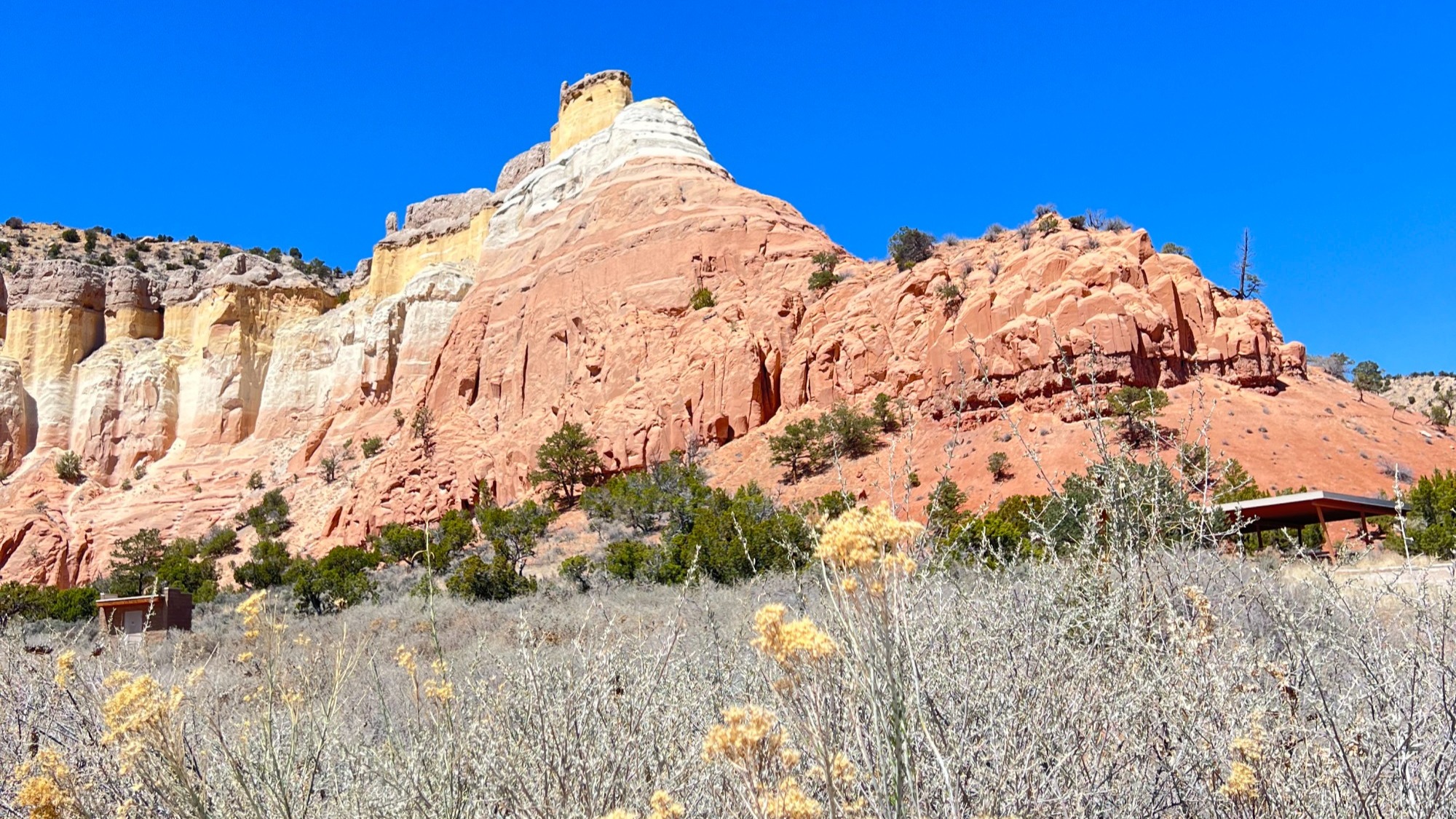 A red rock bluff above a dry grassy field.