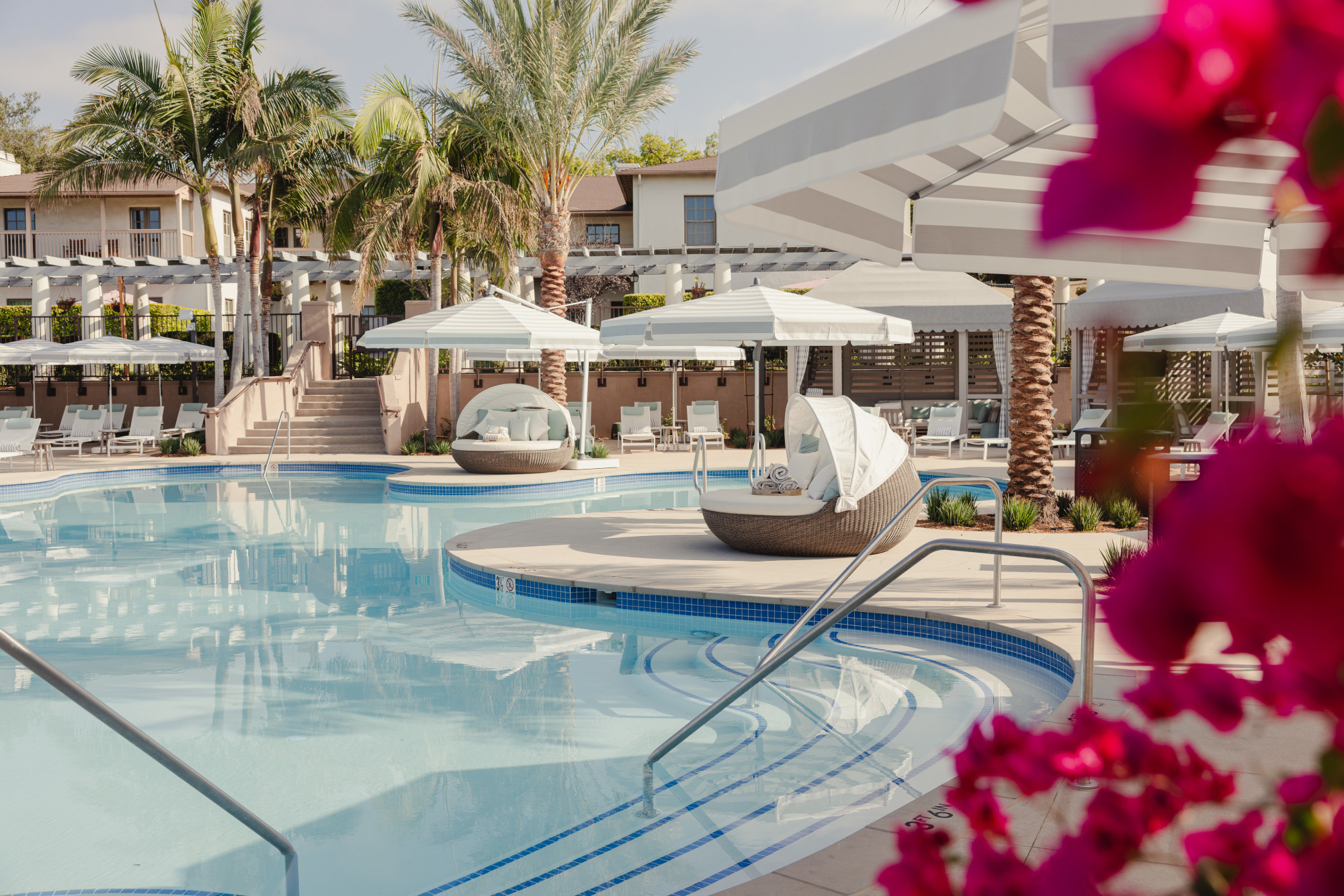 a hotel pool surrounded by white cabanas