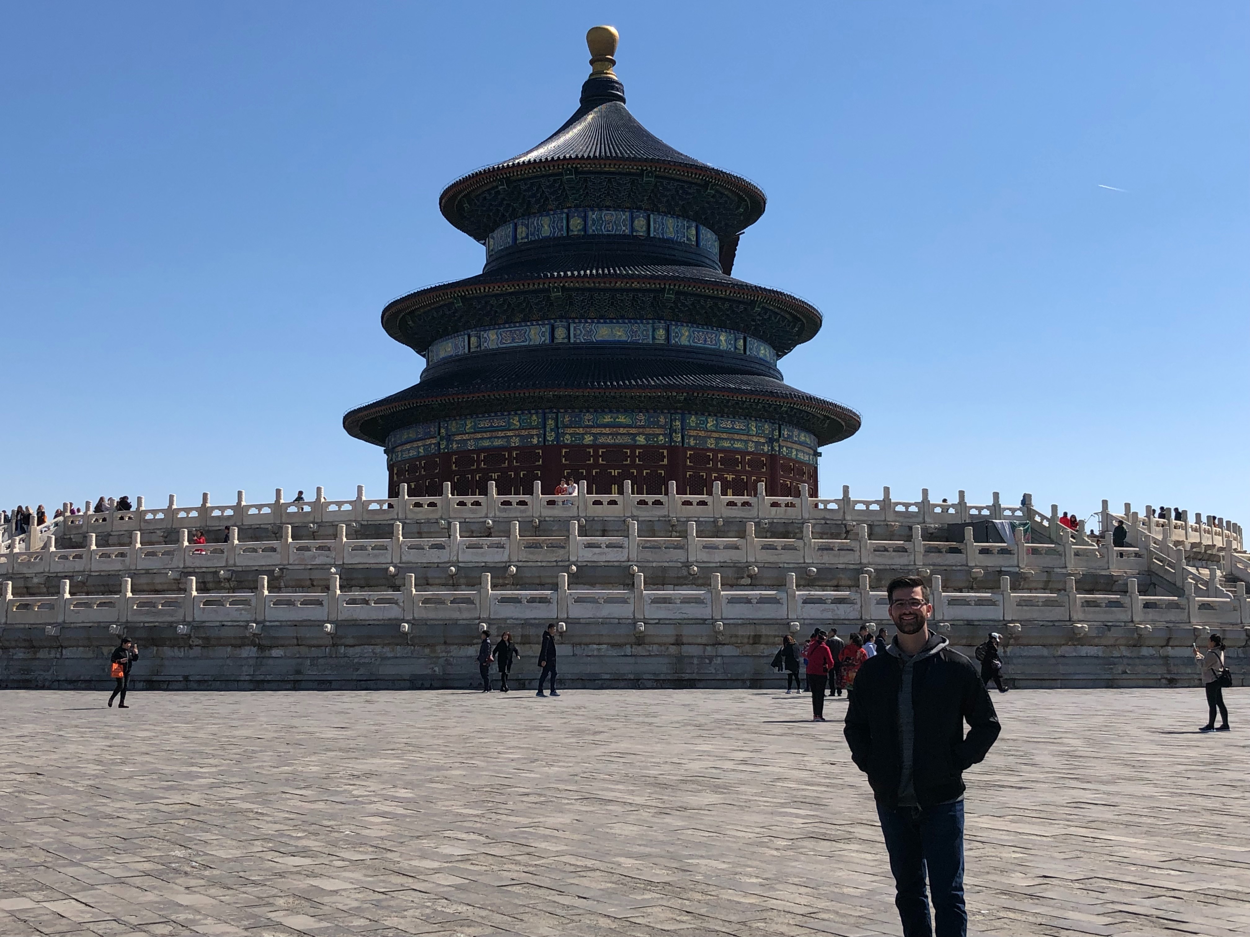 A person standing and posing for a photograph in front of a temple during the daytime