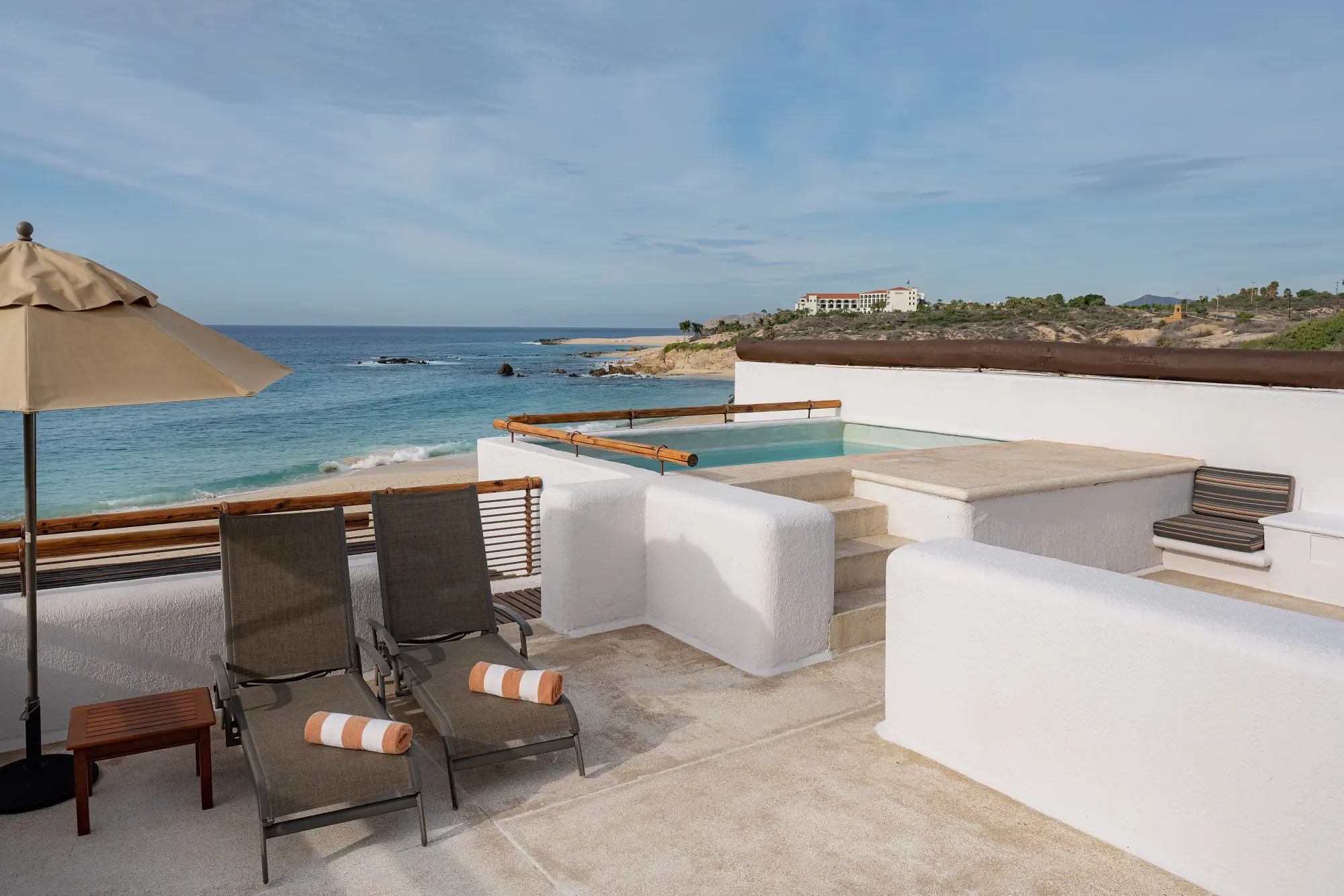 A few loungers on a private terrace, with a small set of stairs leading to a plunge pool, all just feet a away from the ocean
