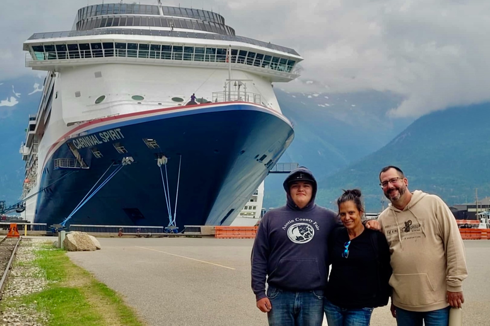 Advisors posing in front of the Carnival Spirit cruise ship with mountains in the background and overcast skies.
