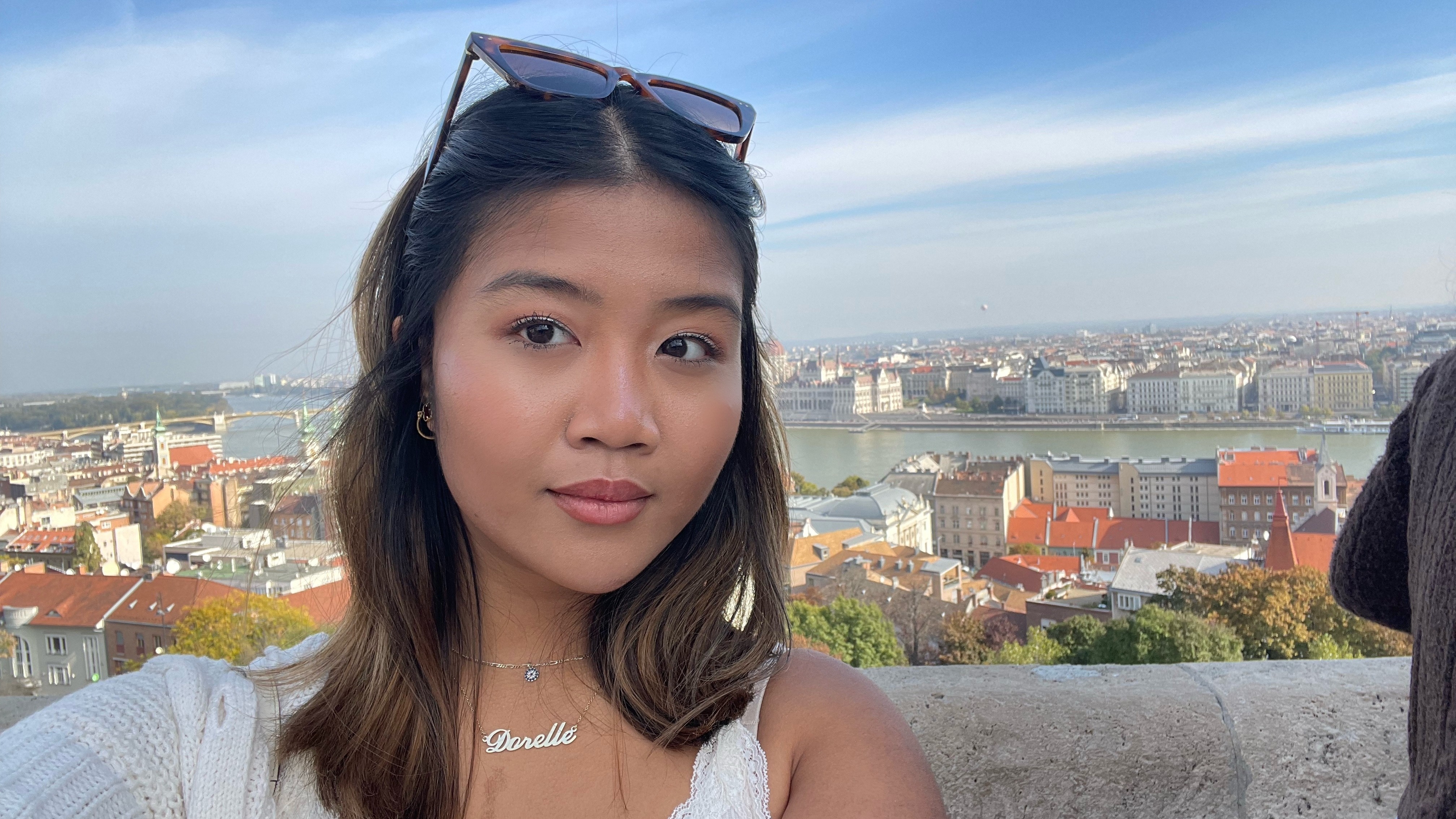 A selfie of a woman with medium-length hair and the city behind her.