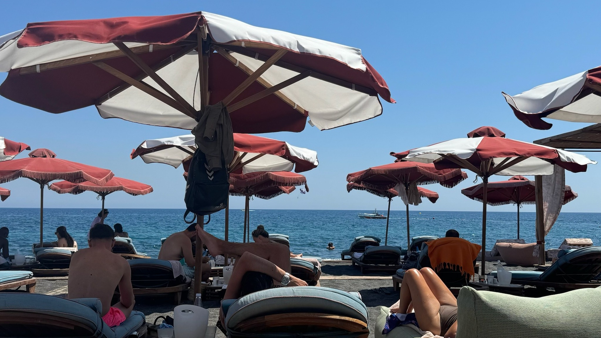 A serene beachside scene with sun loungers and umbrellas under a clear blue sky, overlooking a calm sea.
