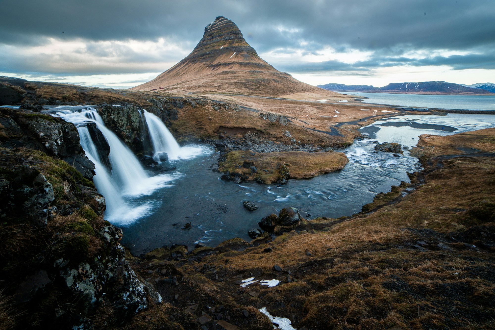 Waterfalls into a water body on a cloudy day.