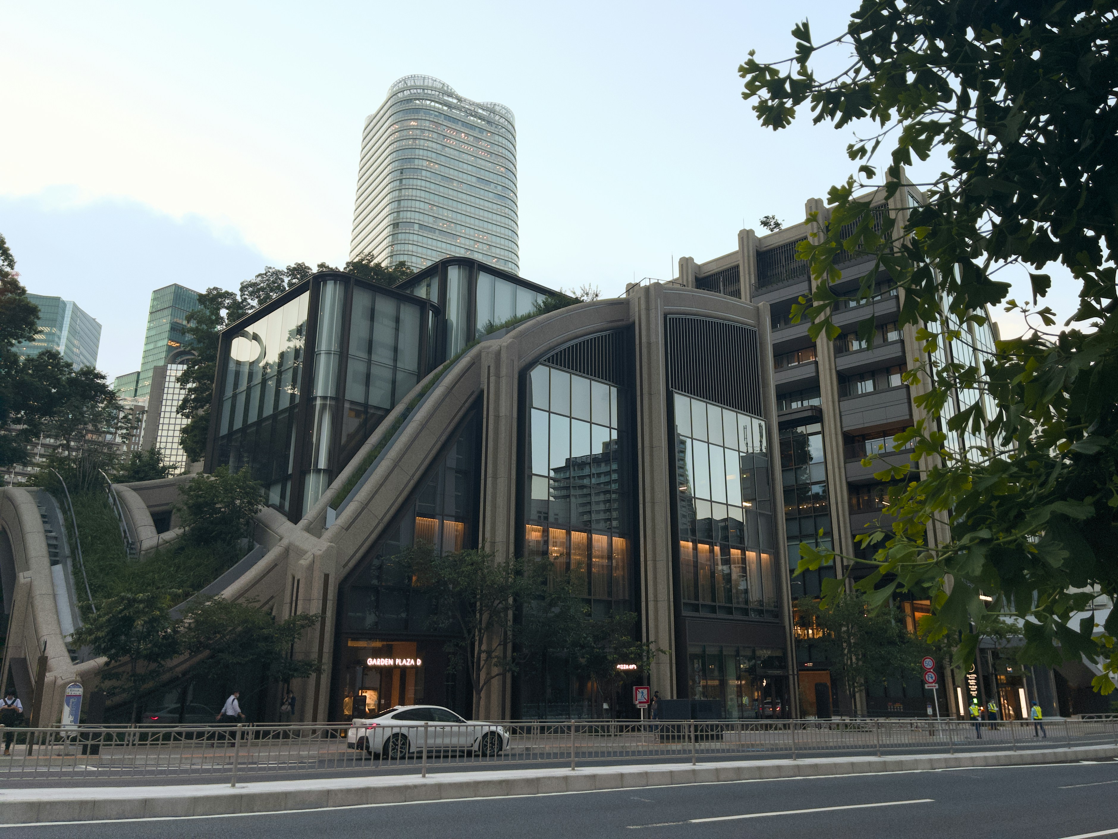 This image shows a car driving down an empty street in front of a modern building.