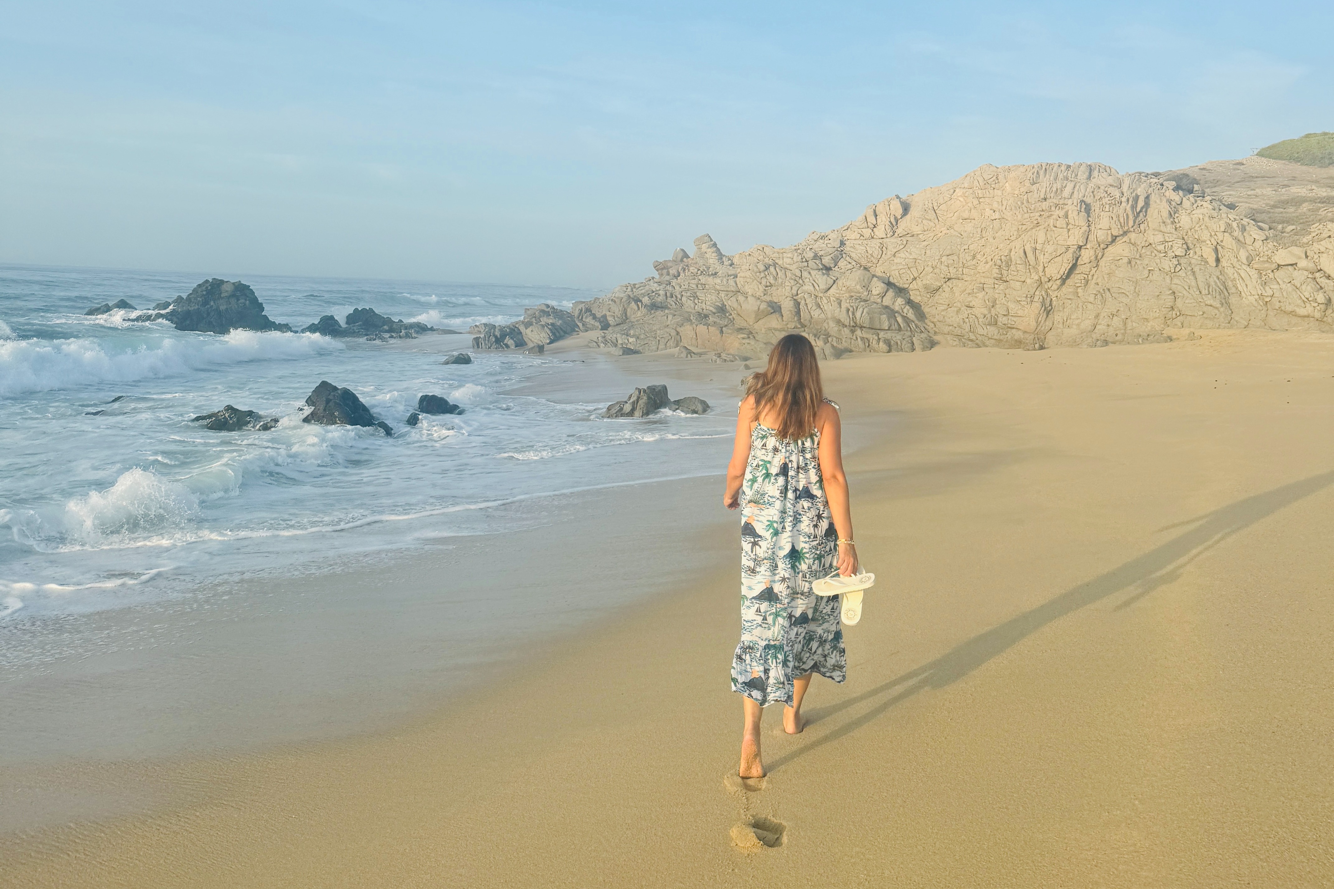 A person walking on a beach next to the water during the daytime
