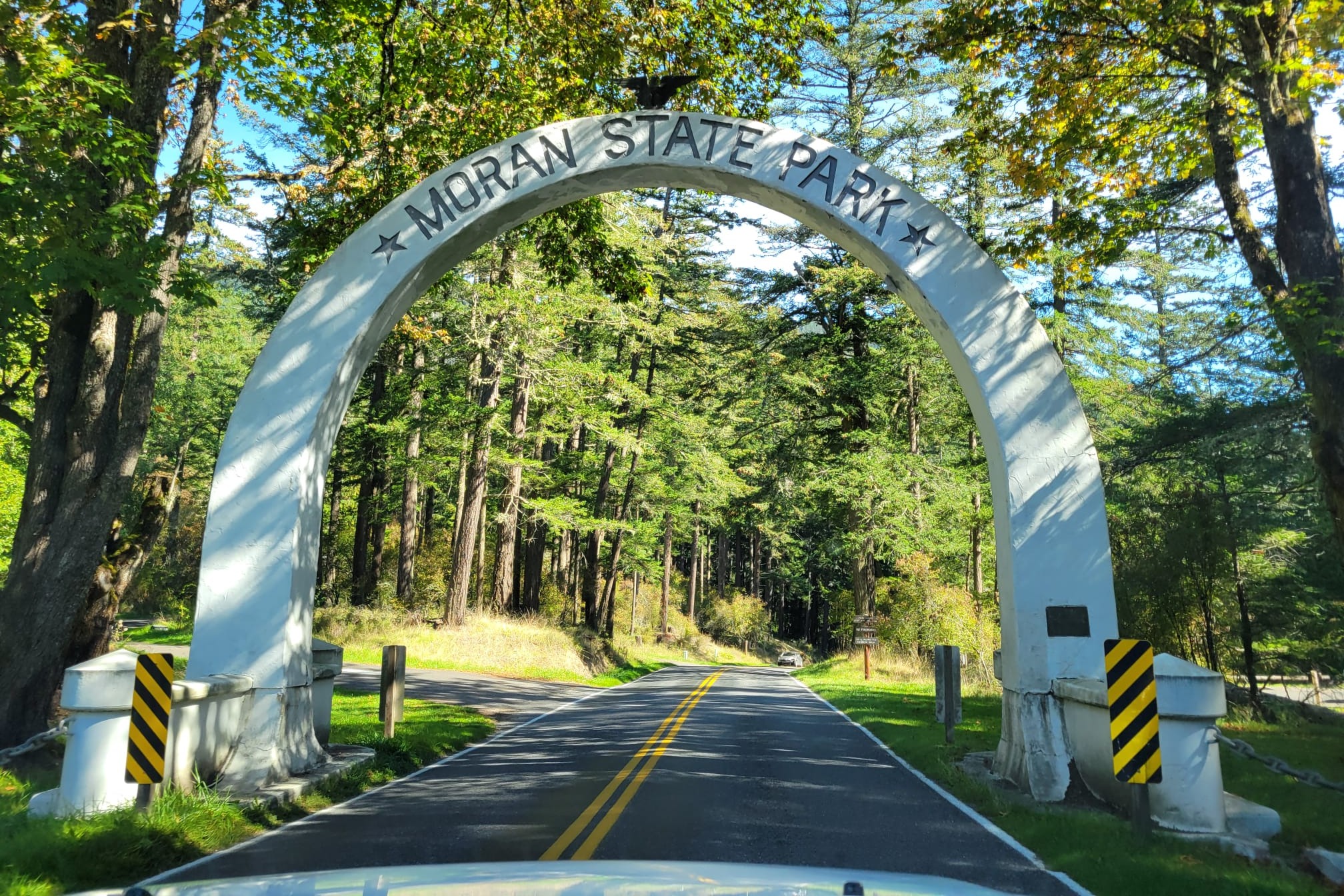 An arched entrance to a forest over a road, reading "Moran State Park"
