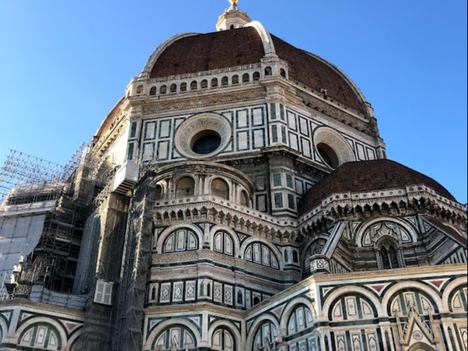 Brown and white building with domes reach toward the clear, blue sky.