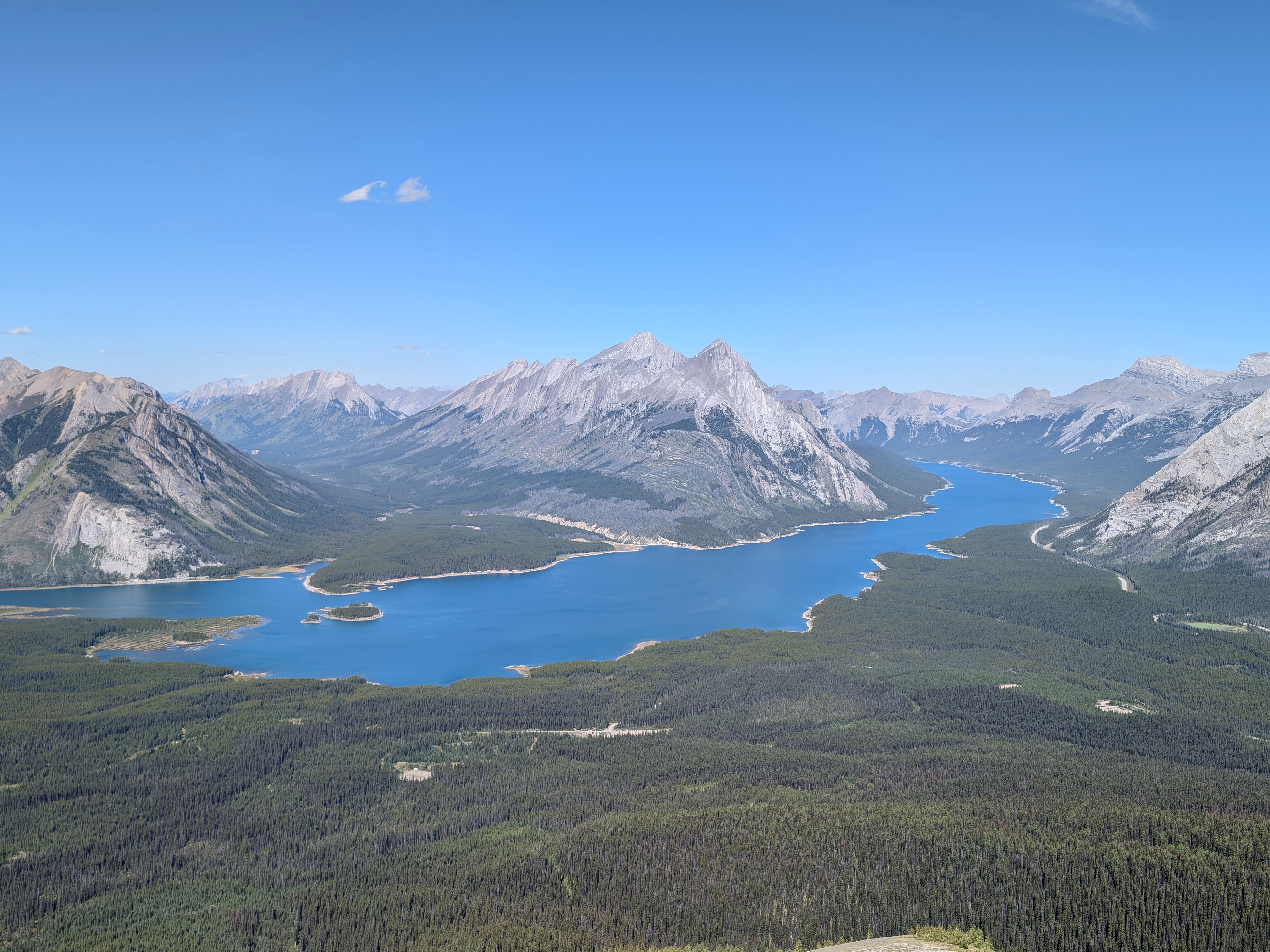A panoramic view of a winding river or lake amidst a mountainous landscape.