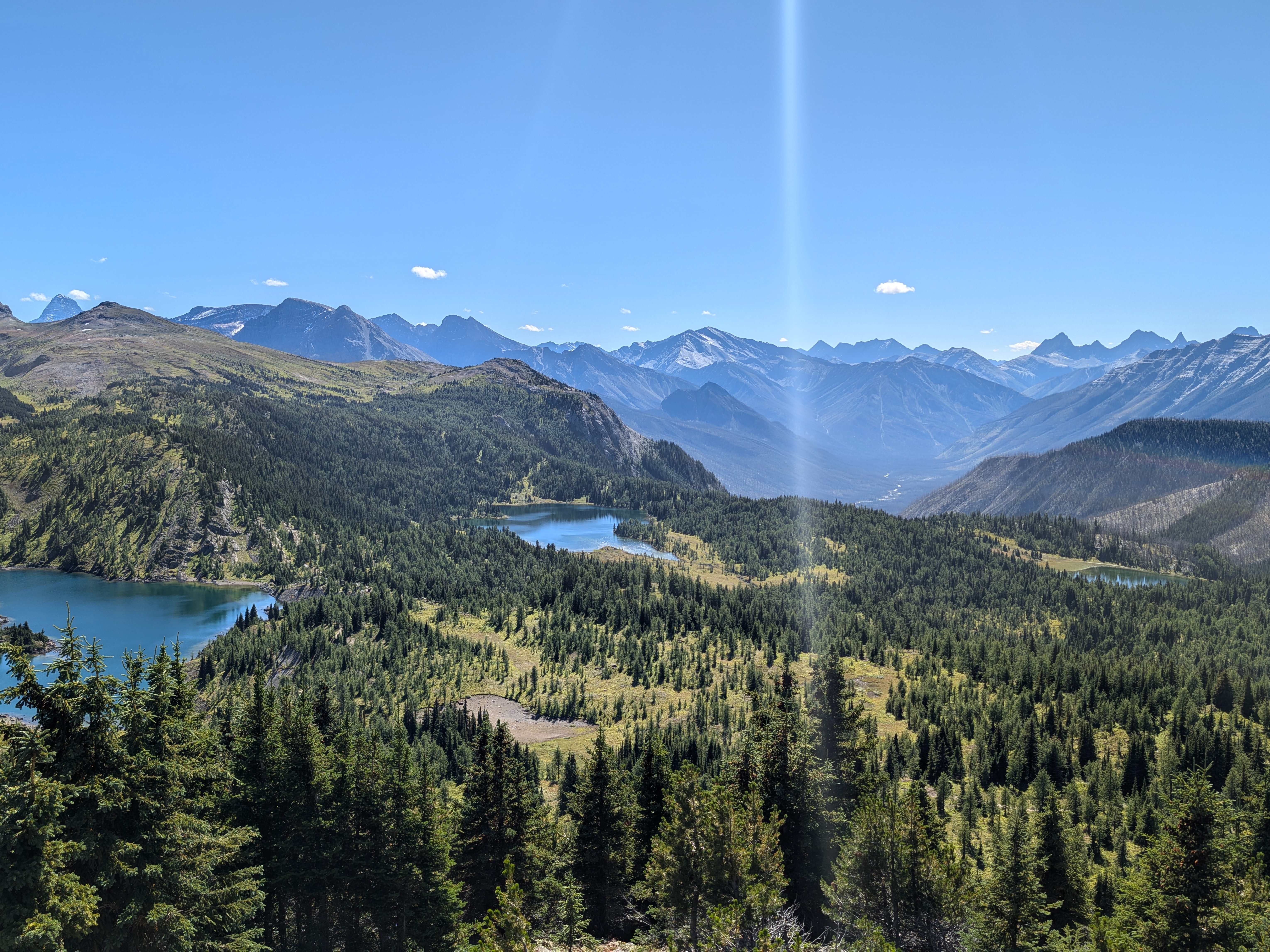 A panoramic view of a mountainous landscape with multiple lakes under a clear blue sky.