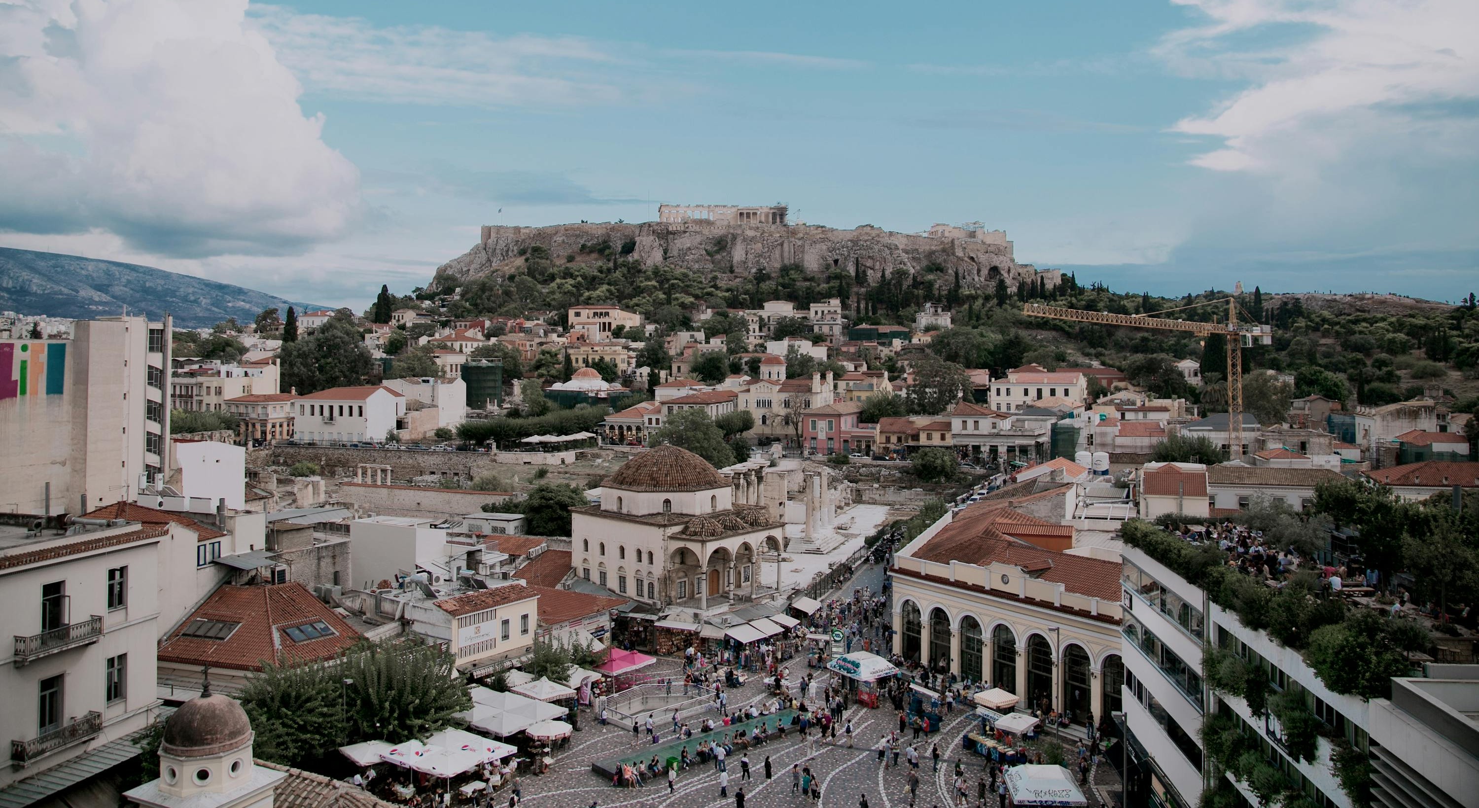 View of Athens, the historic capital of Greece. With many white buildings located on top of a hill.