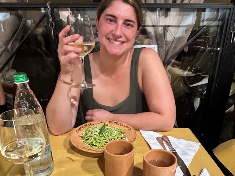 Advisor is dining at a restaurant with a plate of pasta and a glass of wine.