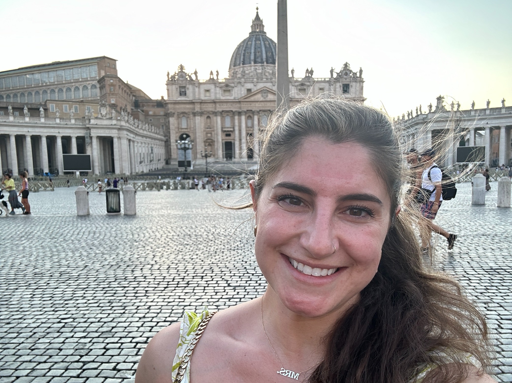 An individual takes a selfie with St. Peter’s Basilica in Vatican City in the background.