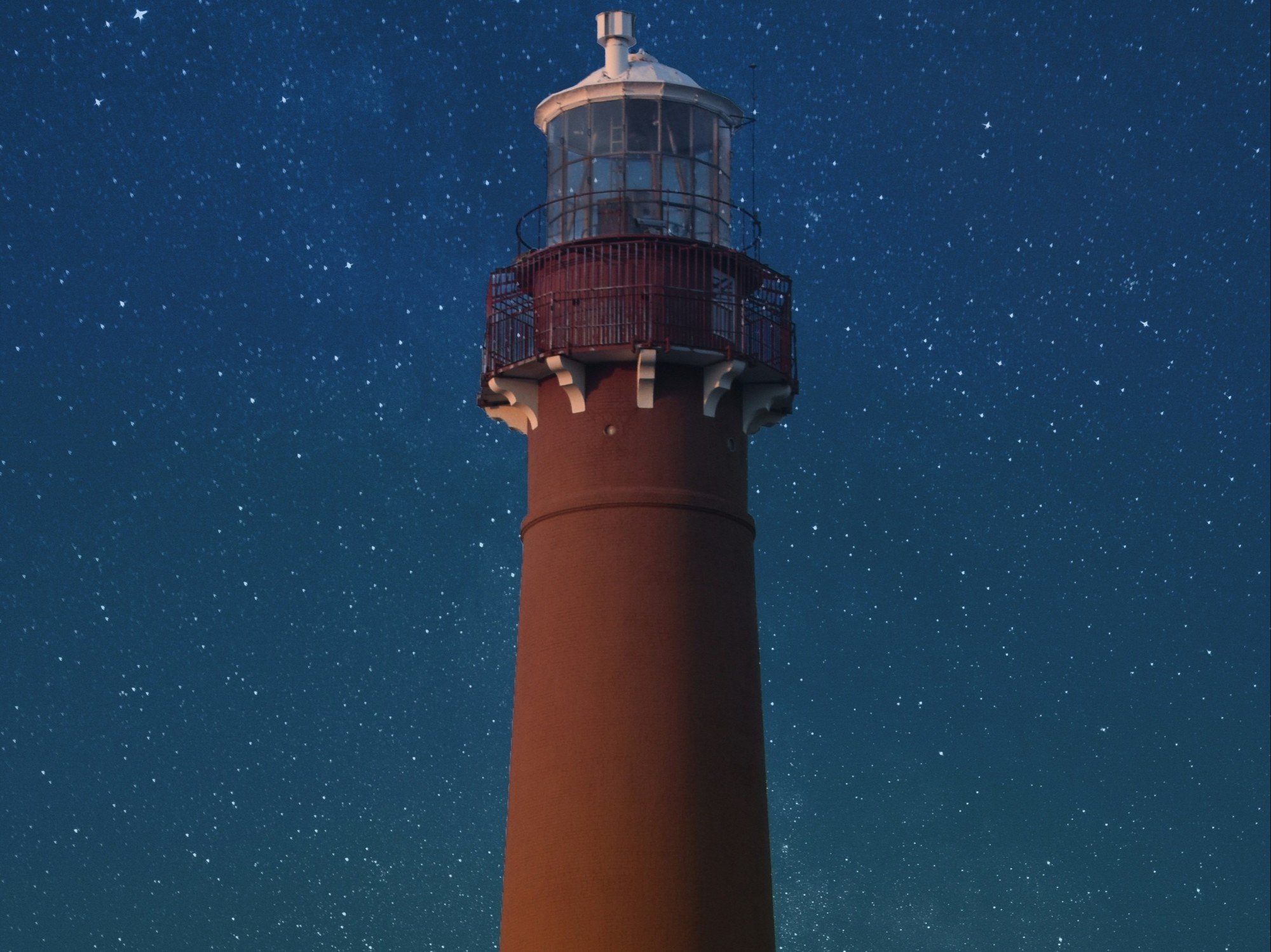 A red lighthouse against a star-filled night sky