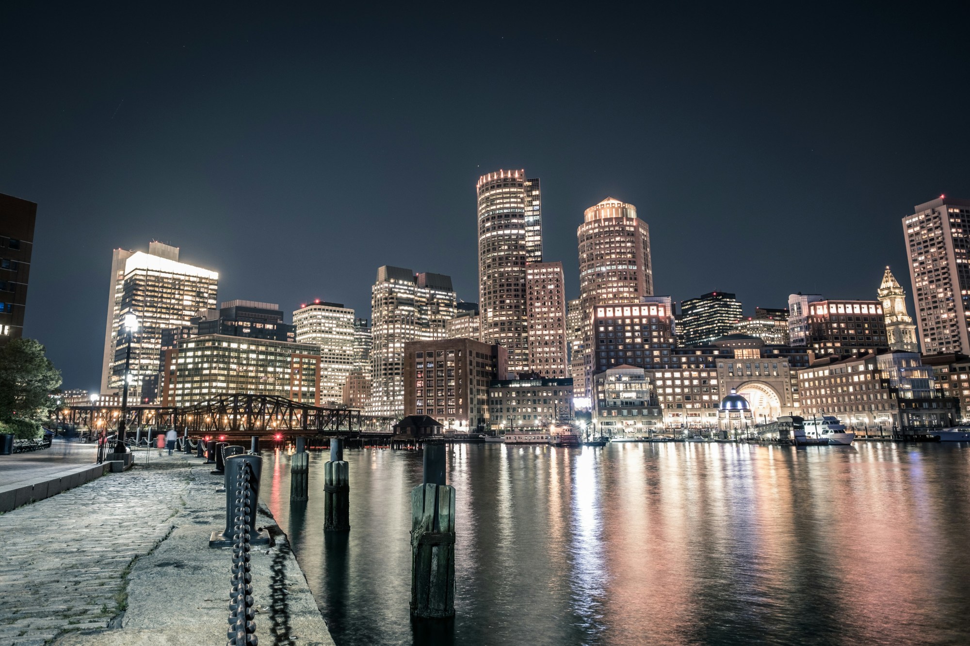 City building light up the night sky as rippled form in a glistening body of water.