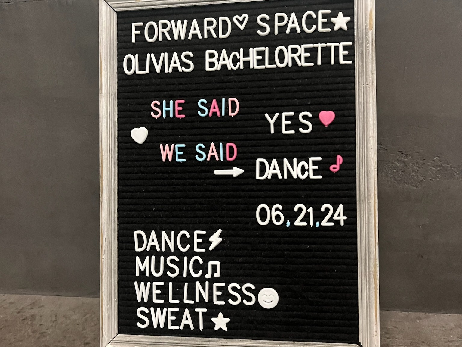 A black letter board with white and pink letters announcing Olivia’s bachelorette party.